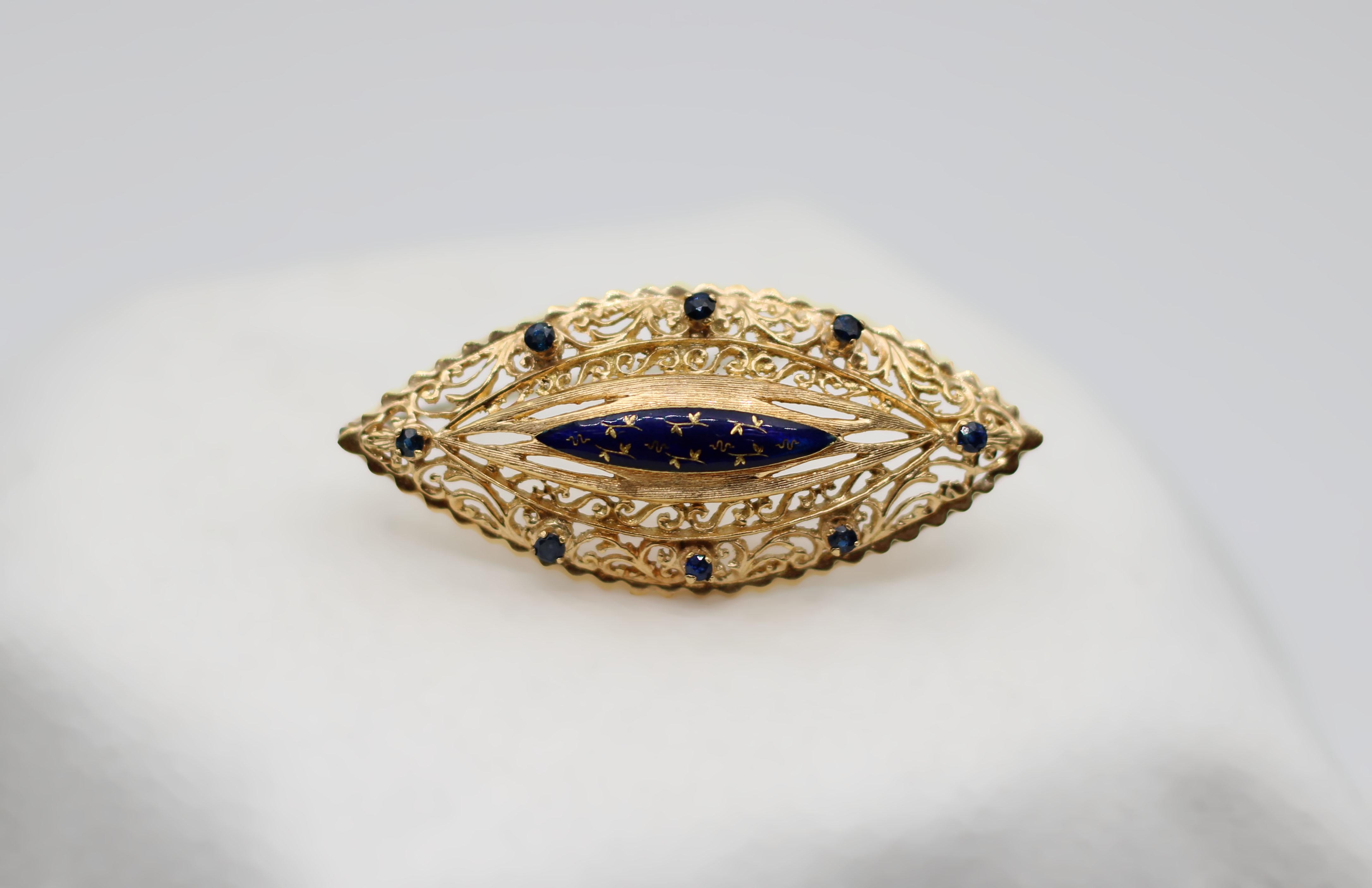 Simplistic in design and curving with Arabesque swirls, this 1960s brooch features a centerpiece of blue enamel surrounded by round-cut sapphires. 

Metal: 14KT Yellow Gold
Total Weight: 9.18g 
Measurements: 50mm x 22mm
Composition: 0.70 Carats of