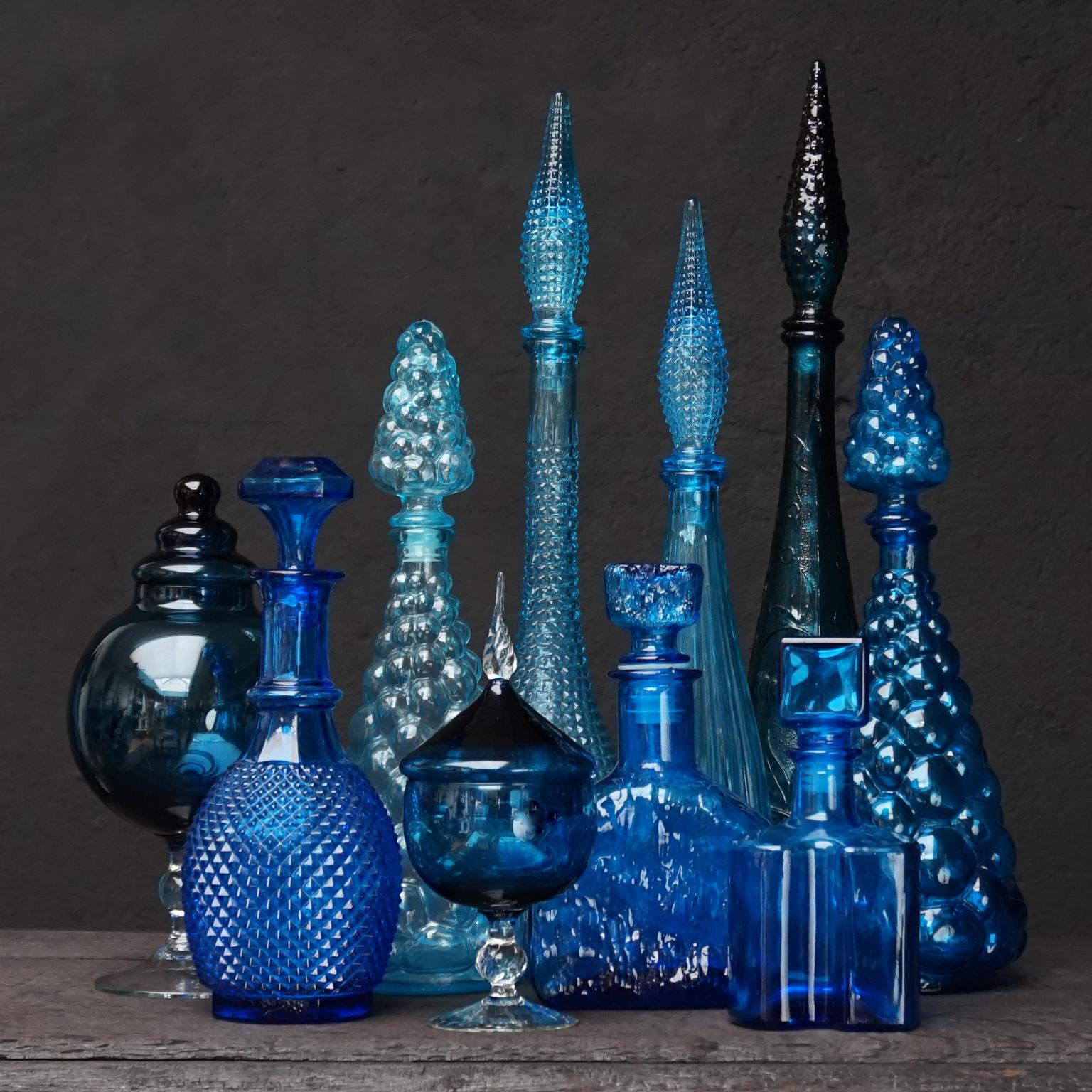 Very decorative blue set of ten different size Italian glass pressed genie bottles, pressed Brutalist decanters and blown clear and blue glass bonbon or candy jars in different shapes and different shades of blue.

Produced in mid-century Empoli,