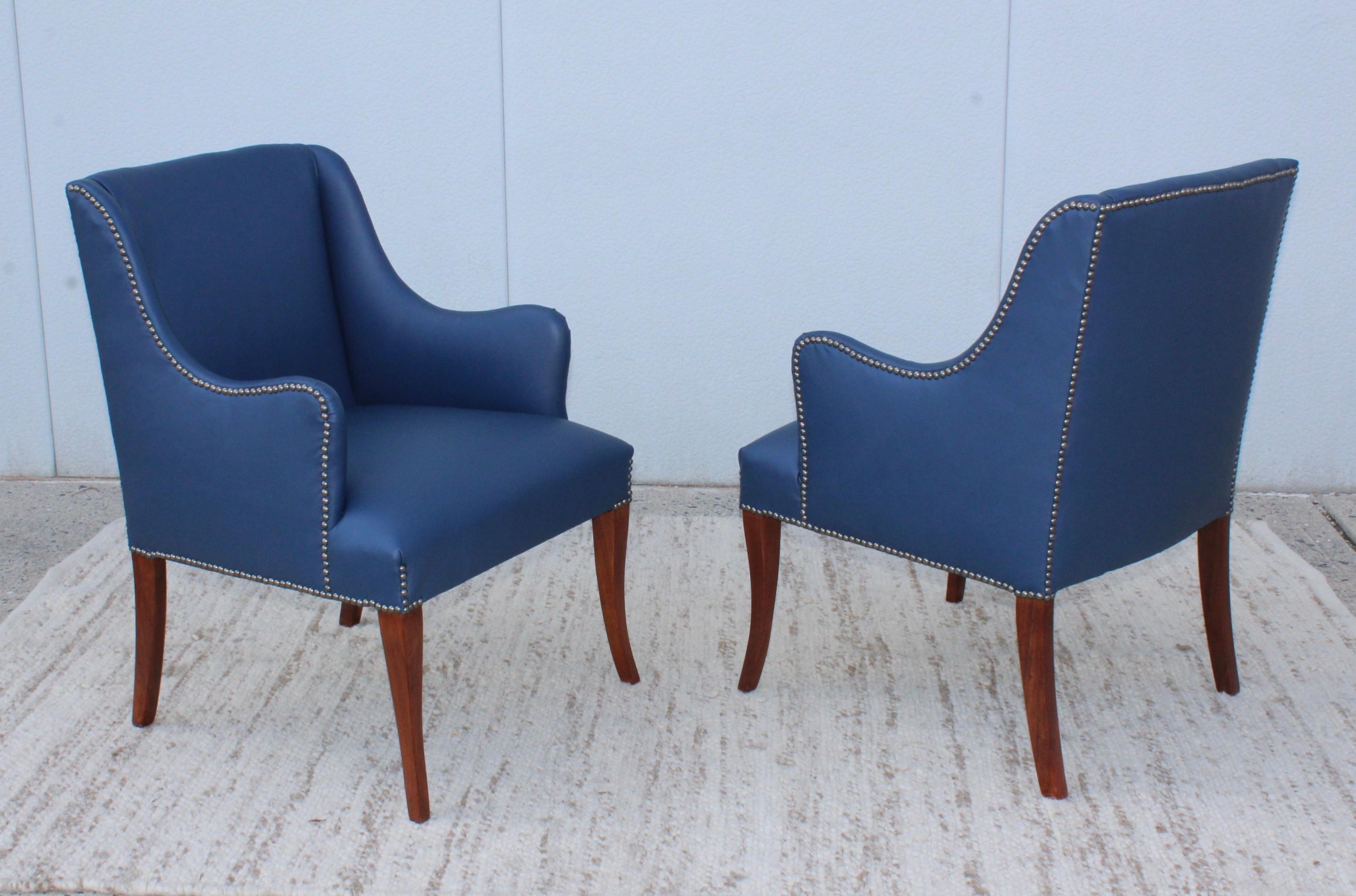 1960s modern blue leather lounge armchairs. Newly reupholstered in blue leather with walnut legs and brass nail detail.