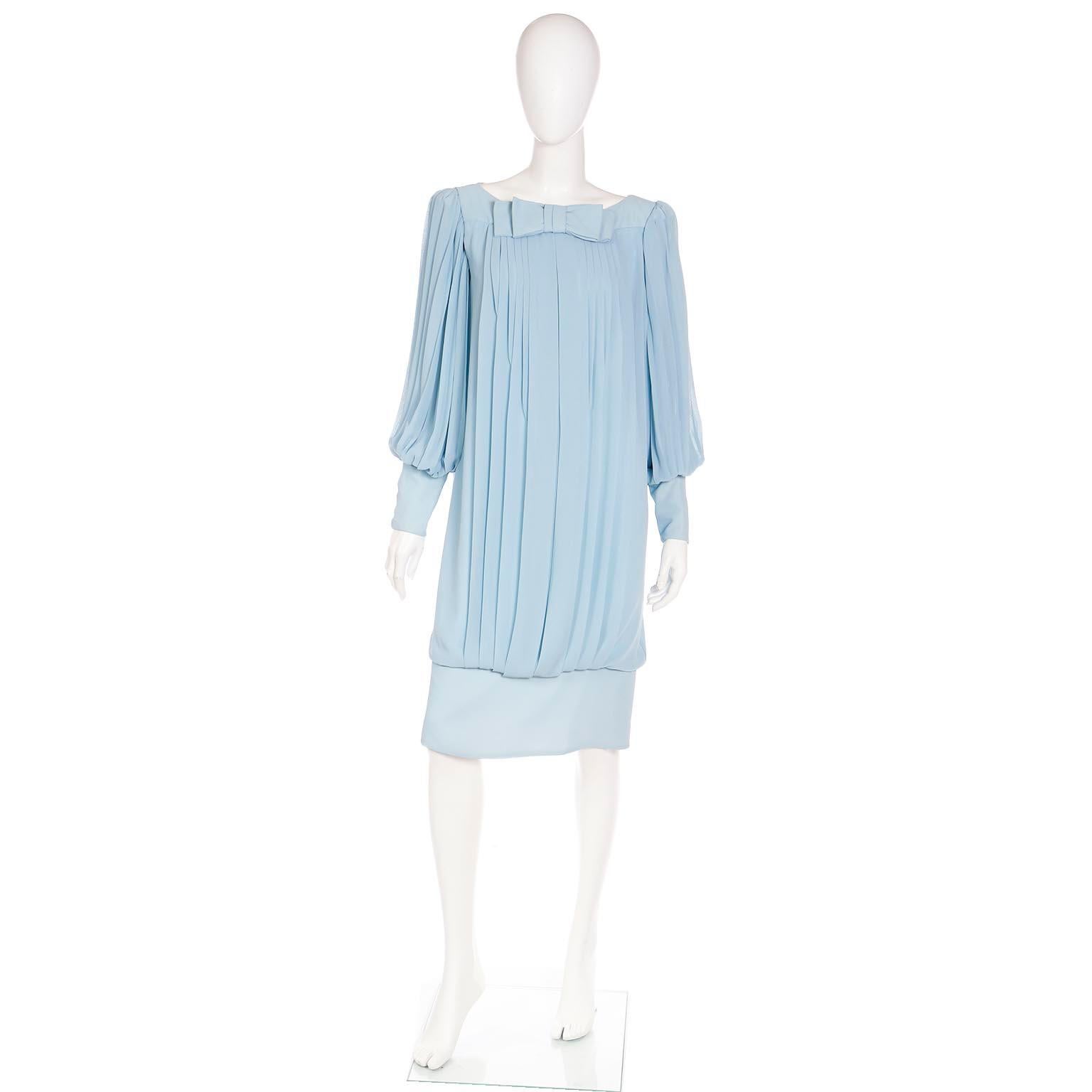 We love unique vintage 1960's dresses and this is such a fabulous blue silk chiffon evening or day dress with a banded hemline in a loosely draped pleated style. The dress has a bow at the center of the neckline and we love the lovely bishop sleeves