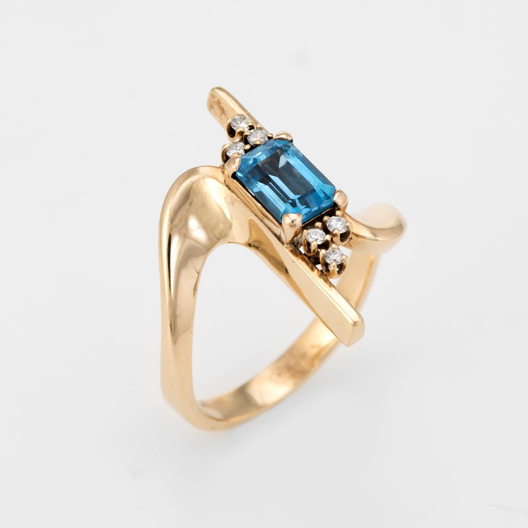 Distinct vintage cocktail ring (circa 1960s), crafted in 14 karat yellow gold. 

Emerald cut blue topaz measures 8mm x 5mm (estimated at 1.50 carats), accented with an estimated 0.12 carats of diamonds (estimated at H-I color and SI2-I1 clarity).