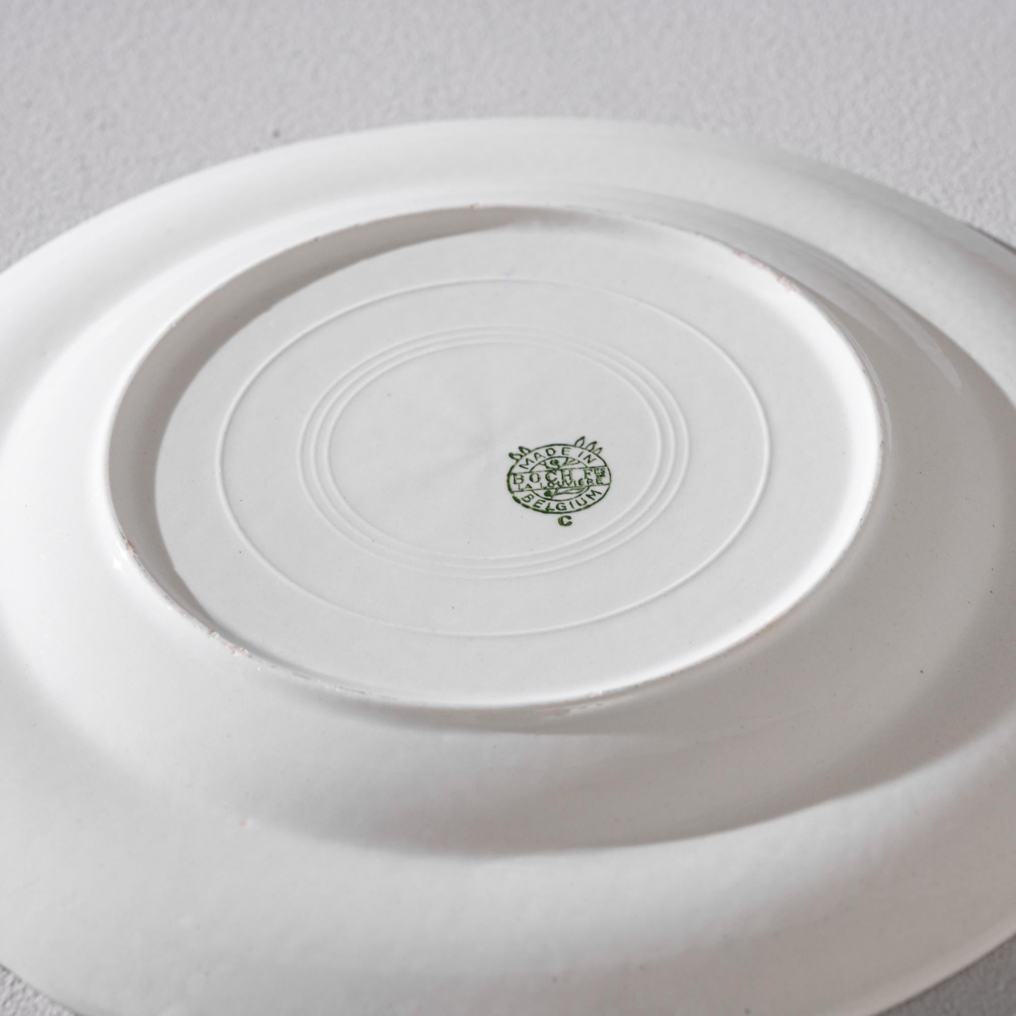 This porcelain plate was manufactured circa 1960 in Belgium by the legendary ceramic company Boch, active in the European market since the 19th century. The delicacy of white china is punctuated by the bold yet gentle flower composition featured in