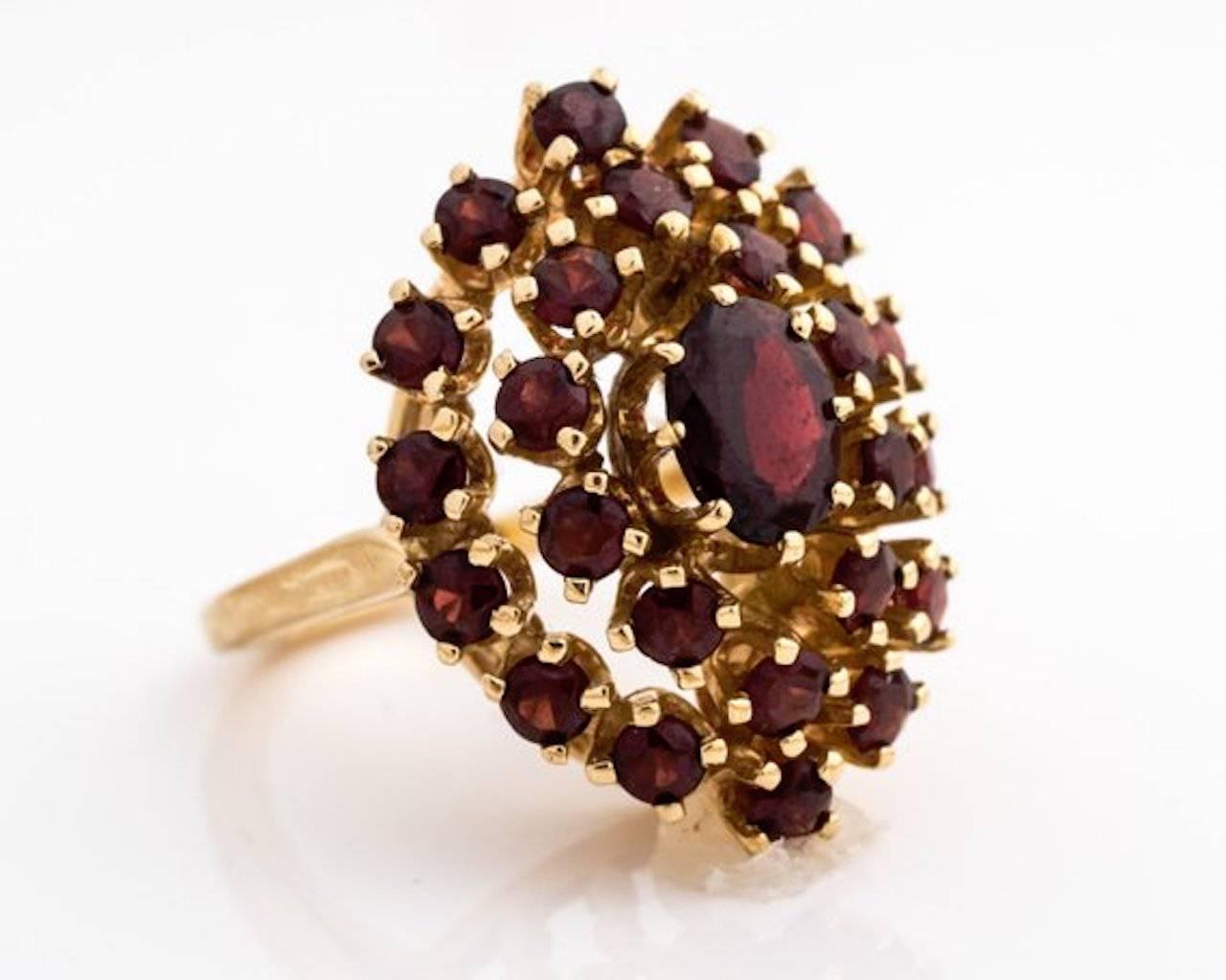 1960s Retro Garnet Cluster Ring -  14k Yellow Gold, Bohemian Garnets

Features an 8- prong set, oval Garnet center stone. Two halos of round garnets surround the center stone. Ten garnets form the inner halo and fourteen garnets form the outer halo.