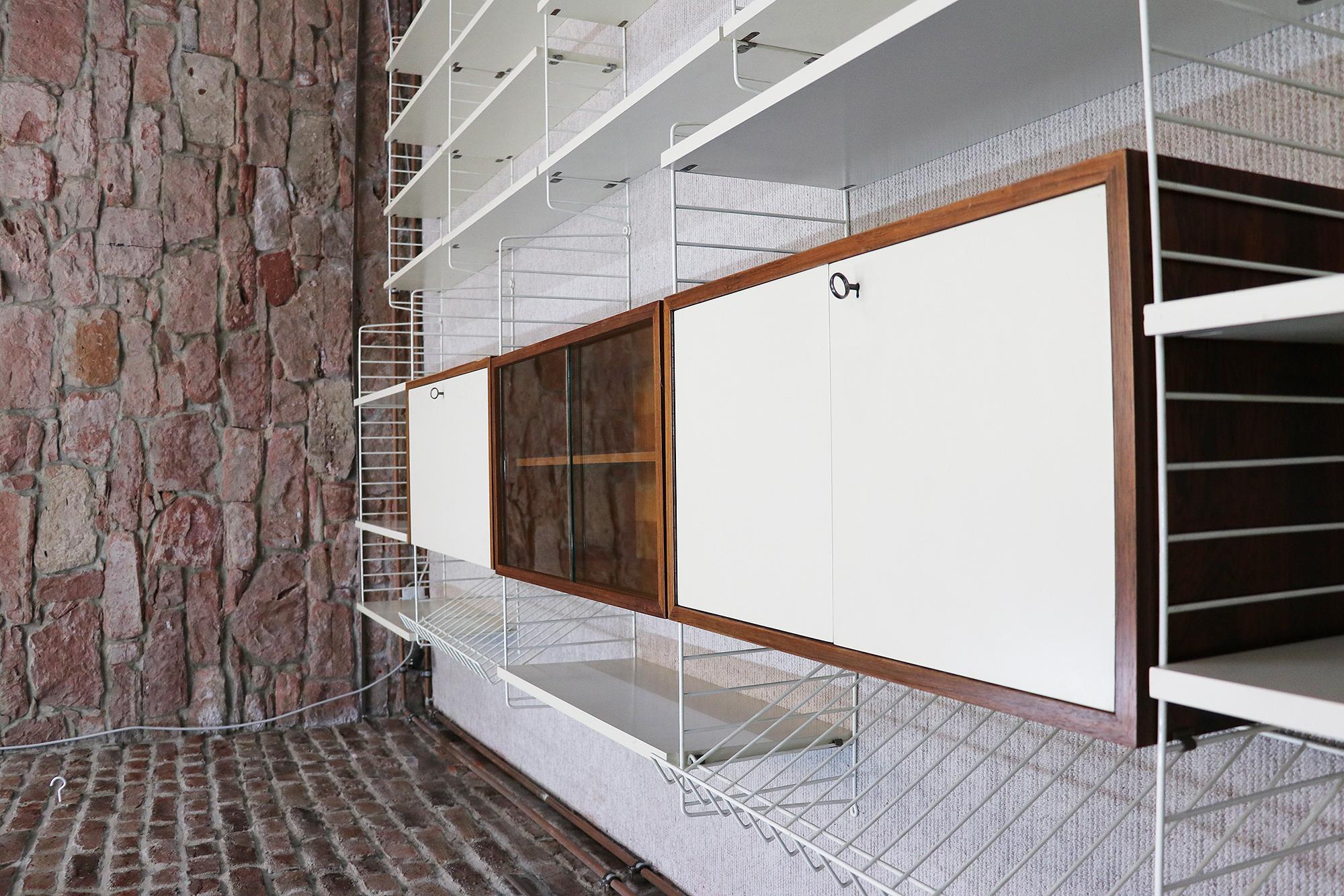 Extra large modular and adaptable shelving system consisting of white lacquered shelving mounted between ladder elements in white lacquered wire steel, two cabinets in white and rosewood, one display cabinet with sliding glass doors in rosewood and