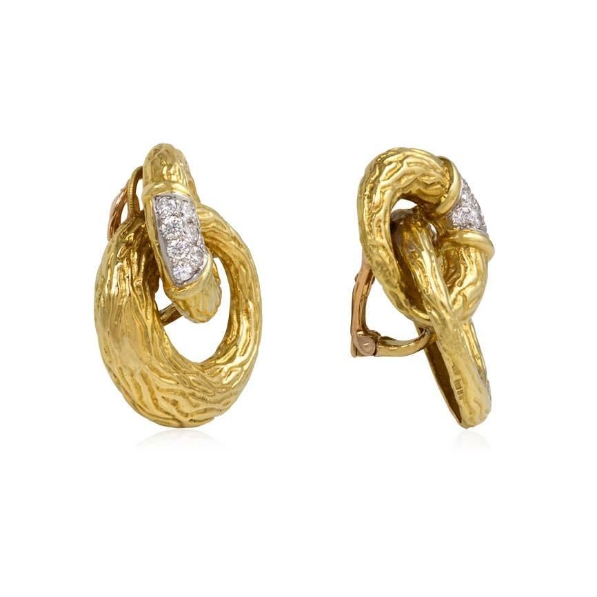 A pair of textured gold earrings designed as a pair of interlocking rings with a pavé diamond segment, in 18k and platinum. Atw. 1.00 ct. diamonds. Boucheron, France. #94562