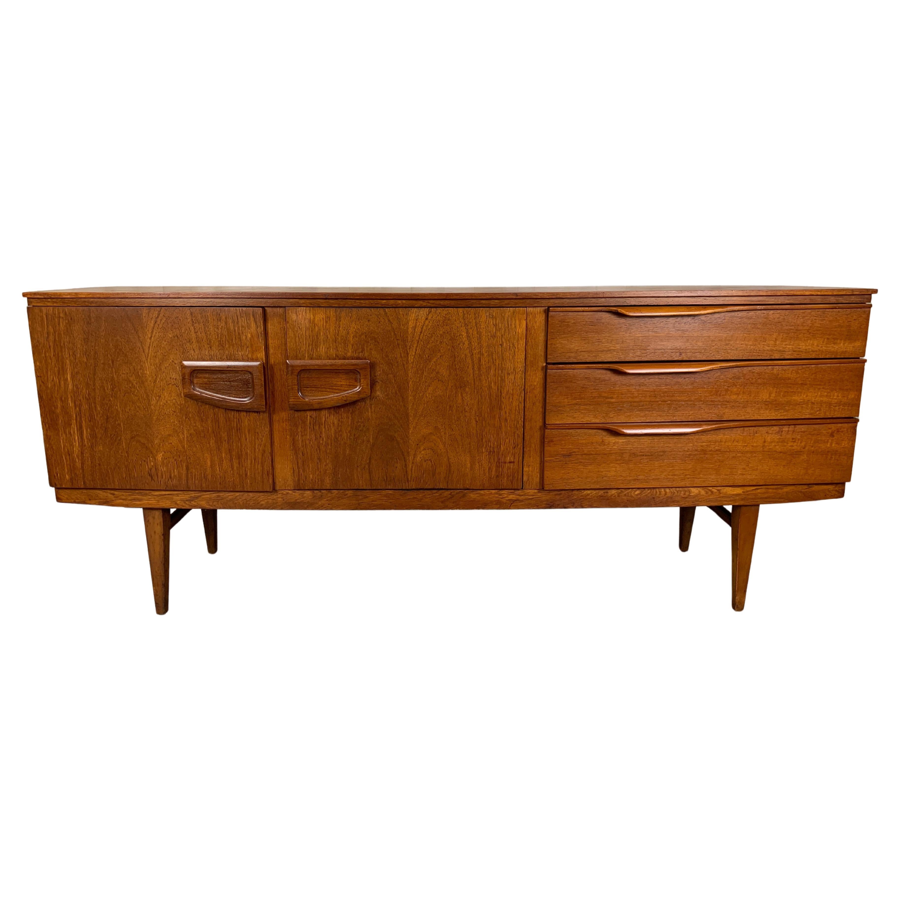 Danish modern style bow front teak credenza with center fold down laminate bar area.