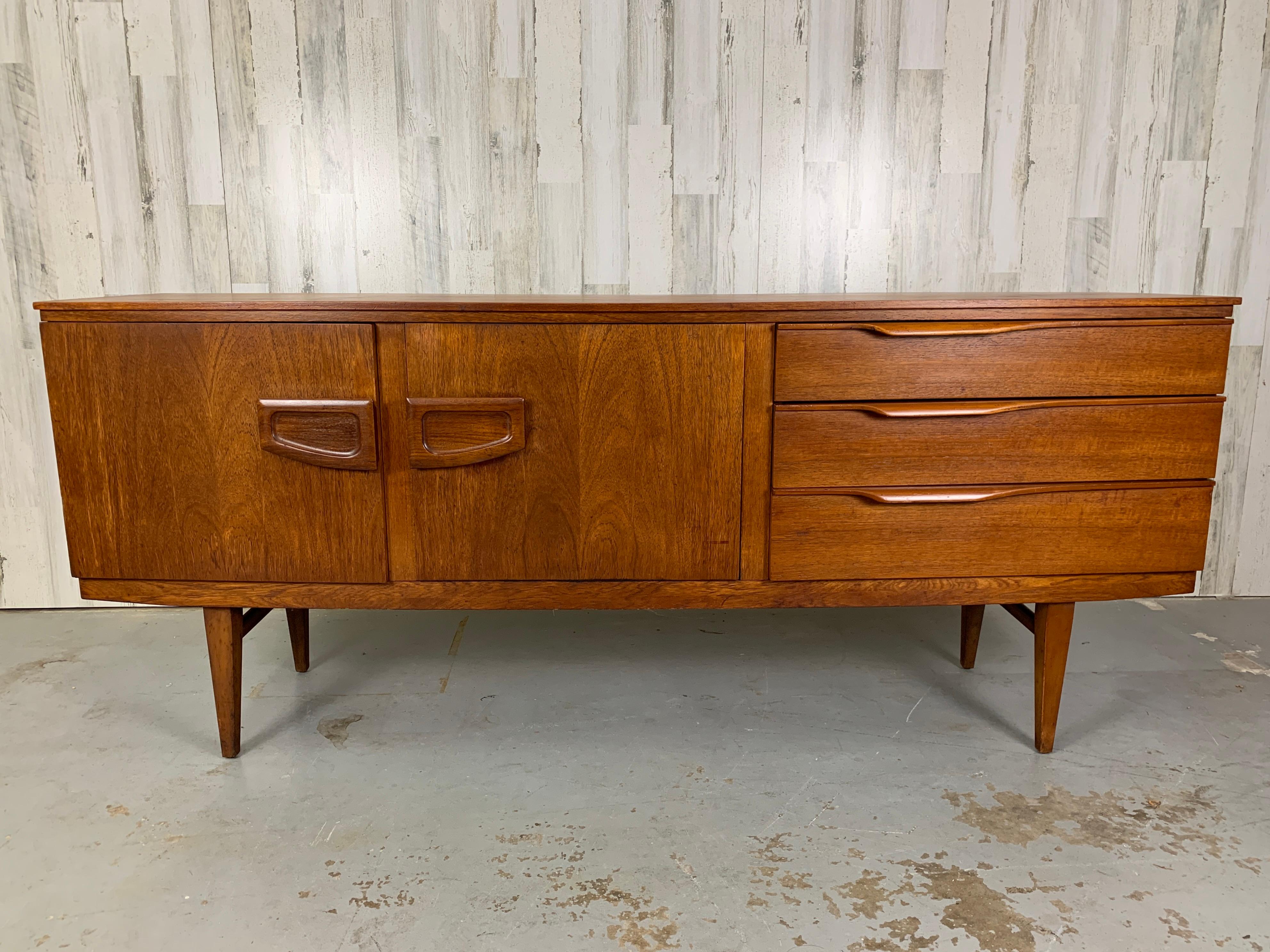 Danish modern style bow front teak credenza with center fold down laminate bar area.