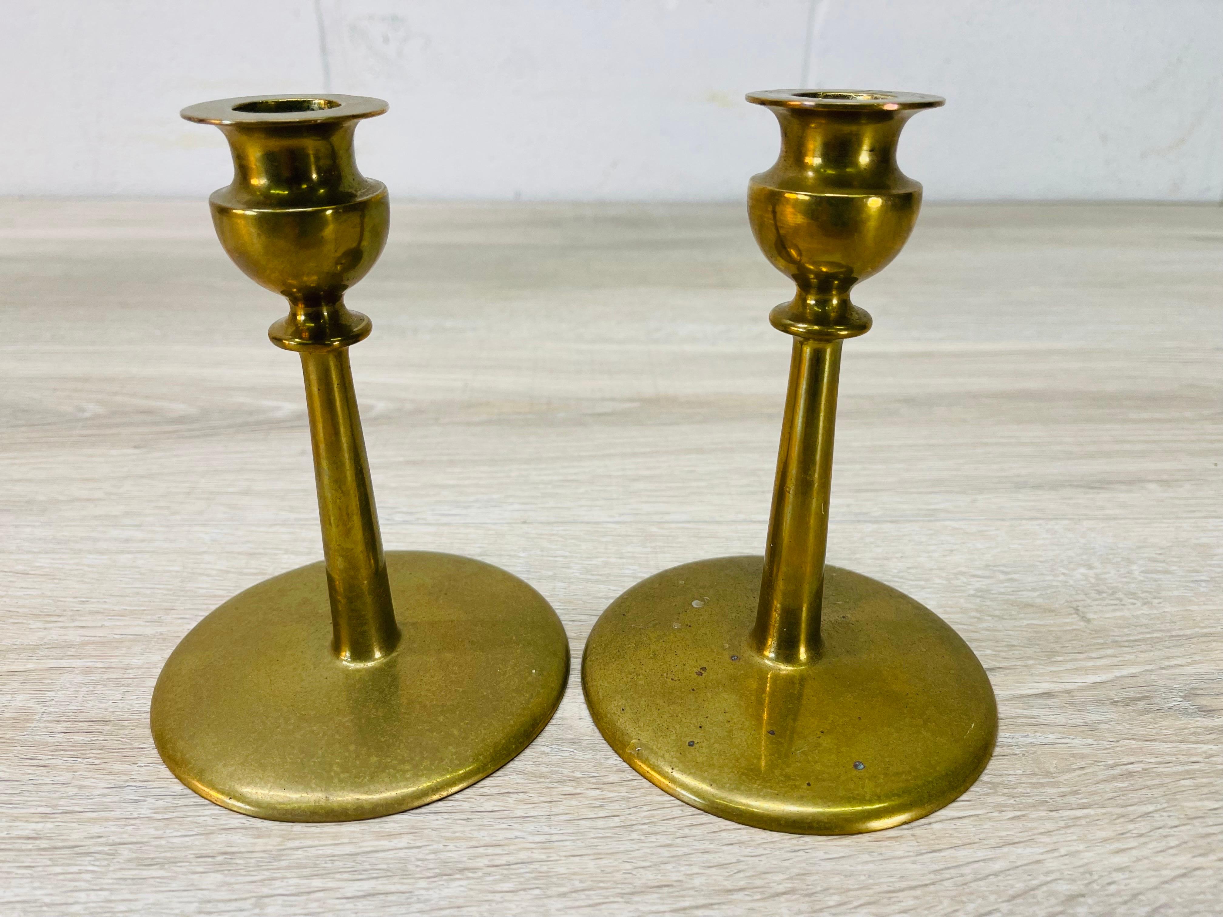 Vintage 1960s pair of solid brass candleholders. The candleholders have a large round base and hold normal sized candles. No marks.