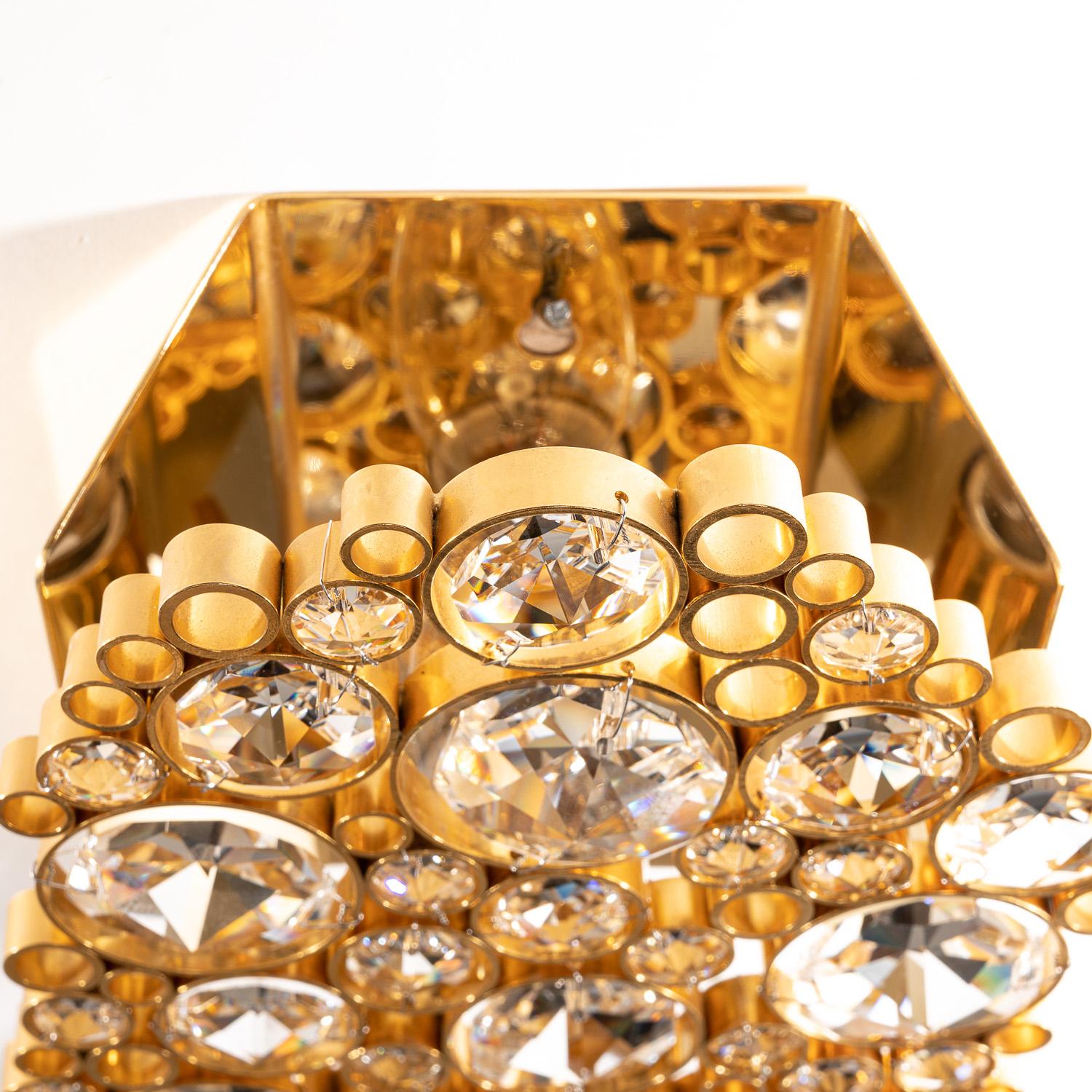 Gorgeous modernist faceted crystal and shiny gilded brass wall sconce designed by Palwa. Gold-plated brass rings mounted with large faceted crystals. High-end piece and excellent craftsmanship from the 20th century.