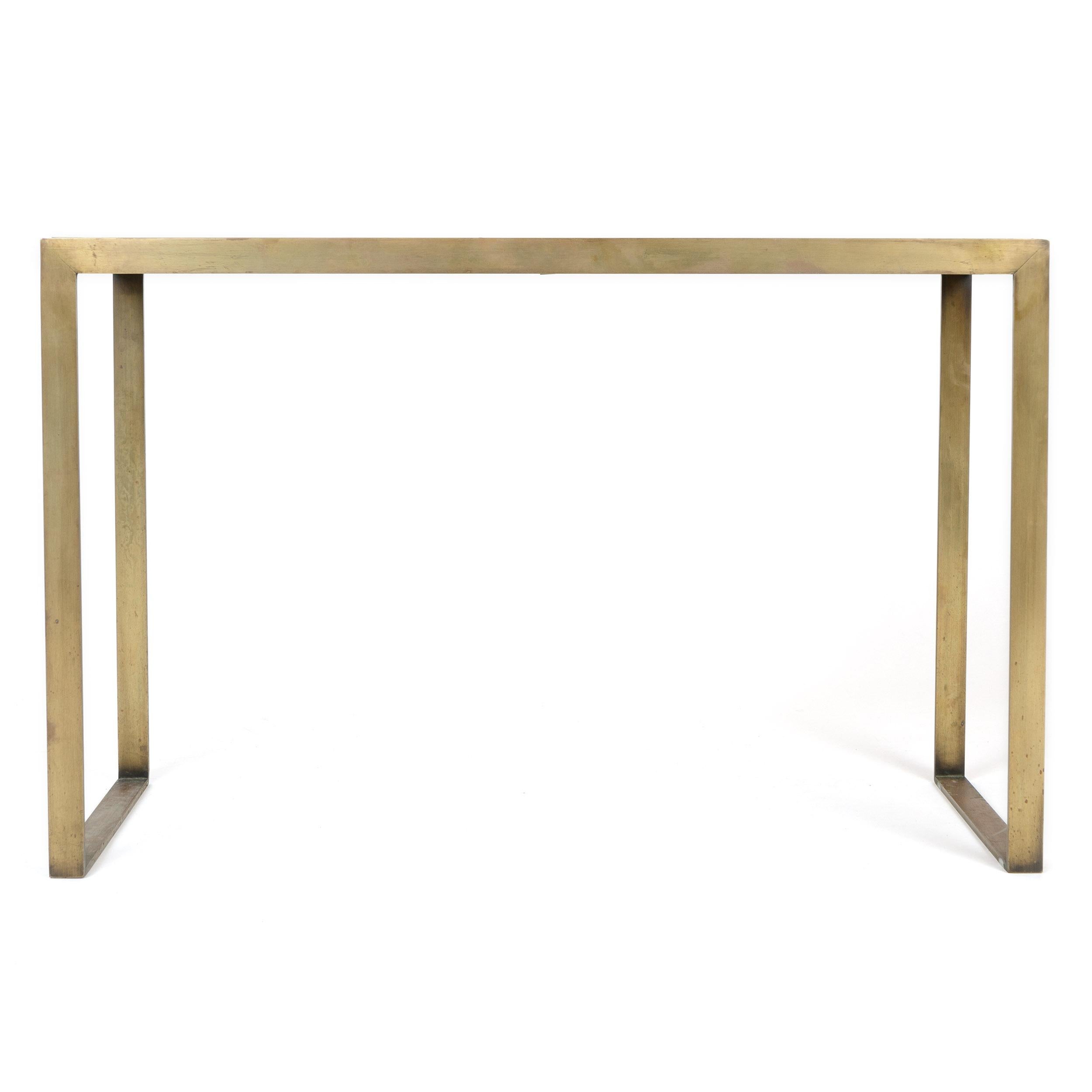 A patinated brass flat-bar framed end table with an inset white top and sled legs.