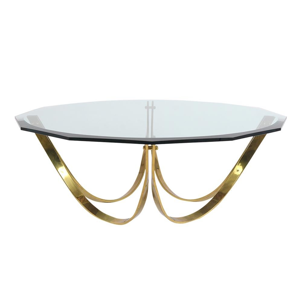 This Mid Century Cocktail Table by Roger Sprunger was produced by Dunbar and features a twelve-sided clear glass top with bevel edge finish in good condition. The top sits on a sleek solid brass curved design base in good condition with normal wear