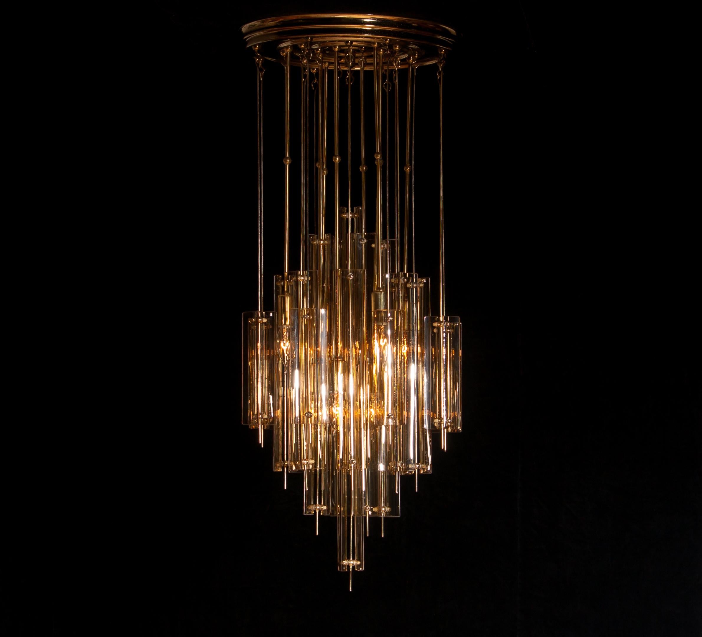 Amazing chandelier in the manner of Verner Panton.
This lamp is made of a gold lacquered metal ceiling plate with brass and fumé glass elements.
It is in a very nice, fair to age, condition.
Period 1960s.
Dimension: Total height 101 cm, ø.41 cm.