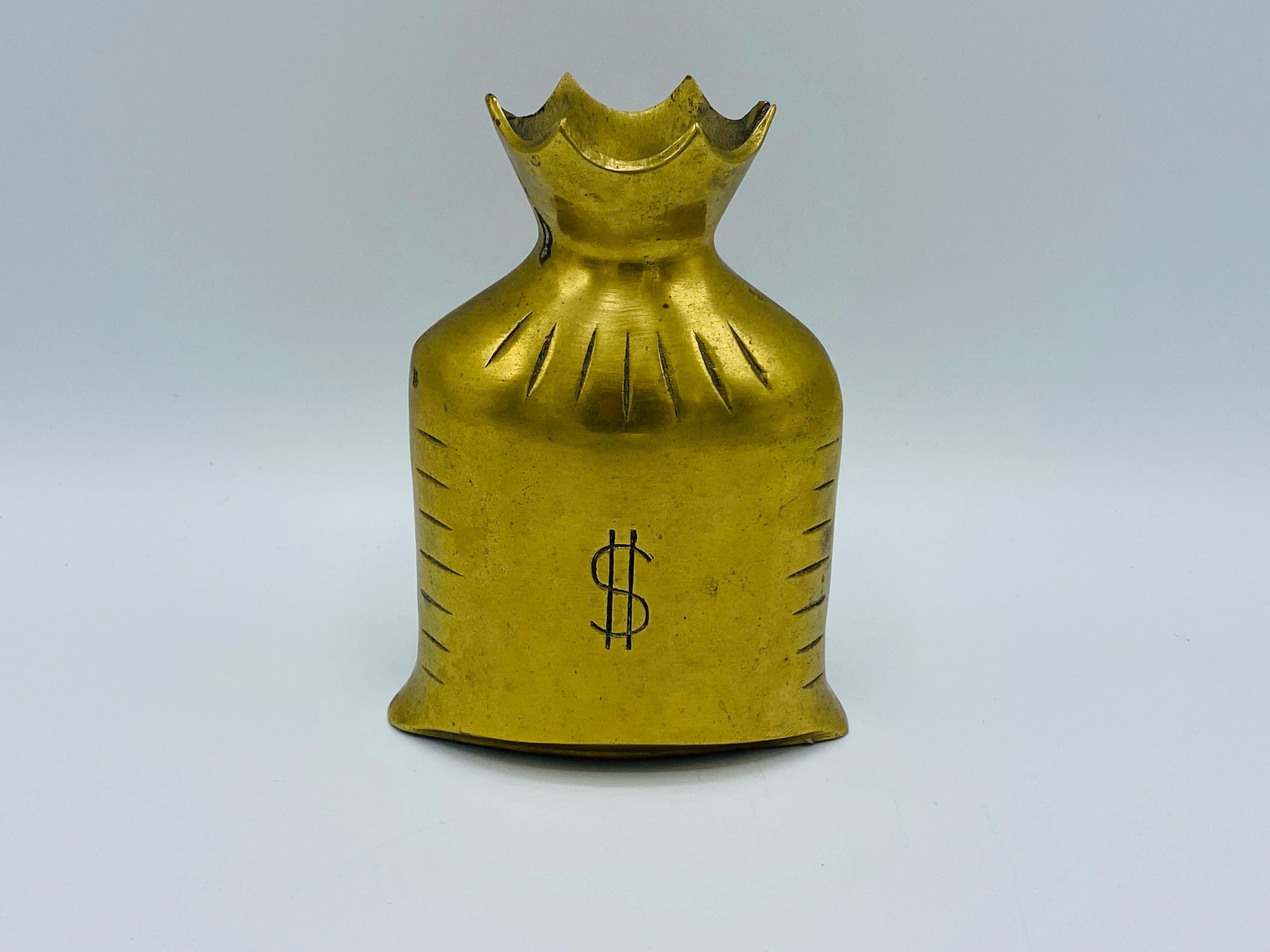 Listed is a playful and unique, 1960s solid-brass money bag. The piece has an opening along the top, perfect for change to use as a small bank. Incredibly heavy, weighing 1.9lbs.