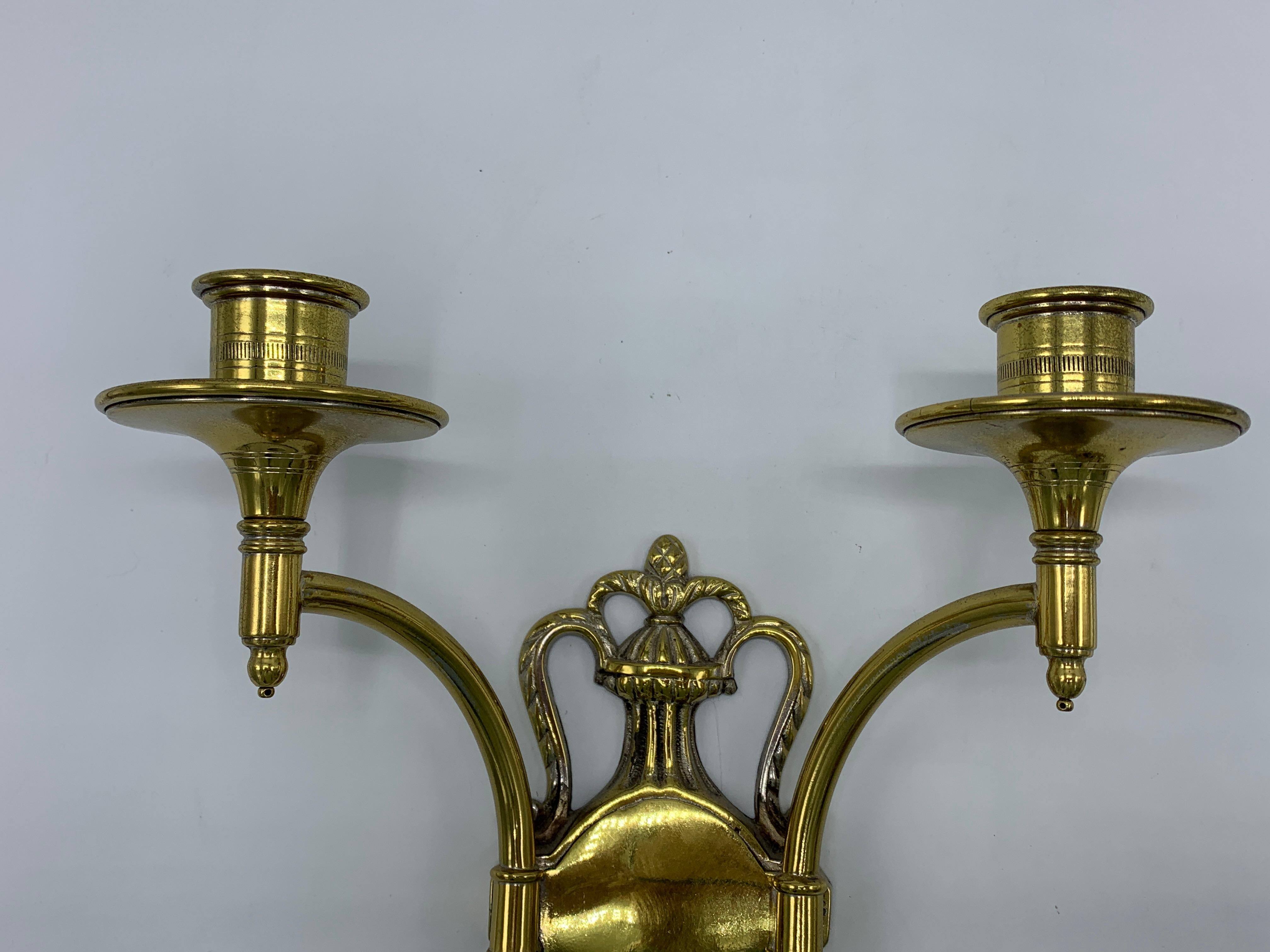 Offered is a pair of 1960s, polished brass shield/crest shaped candlestick wall sconces. Heavy. Marked on backside, 