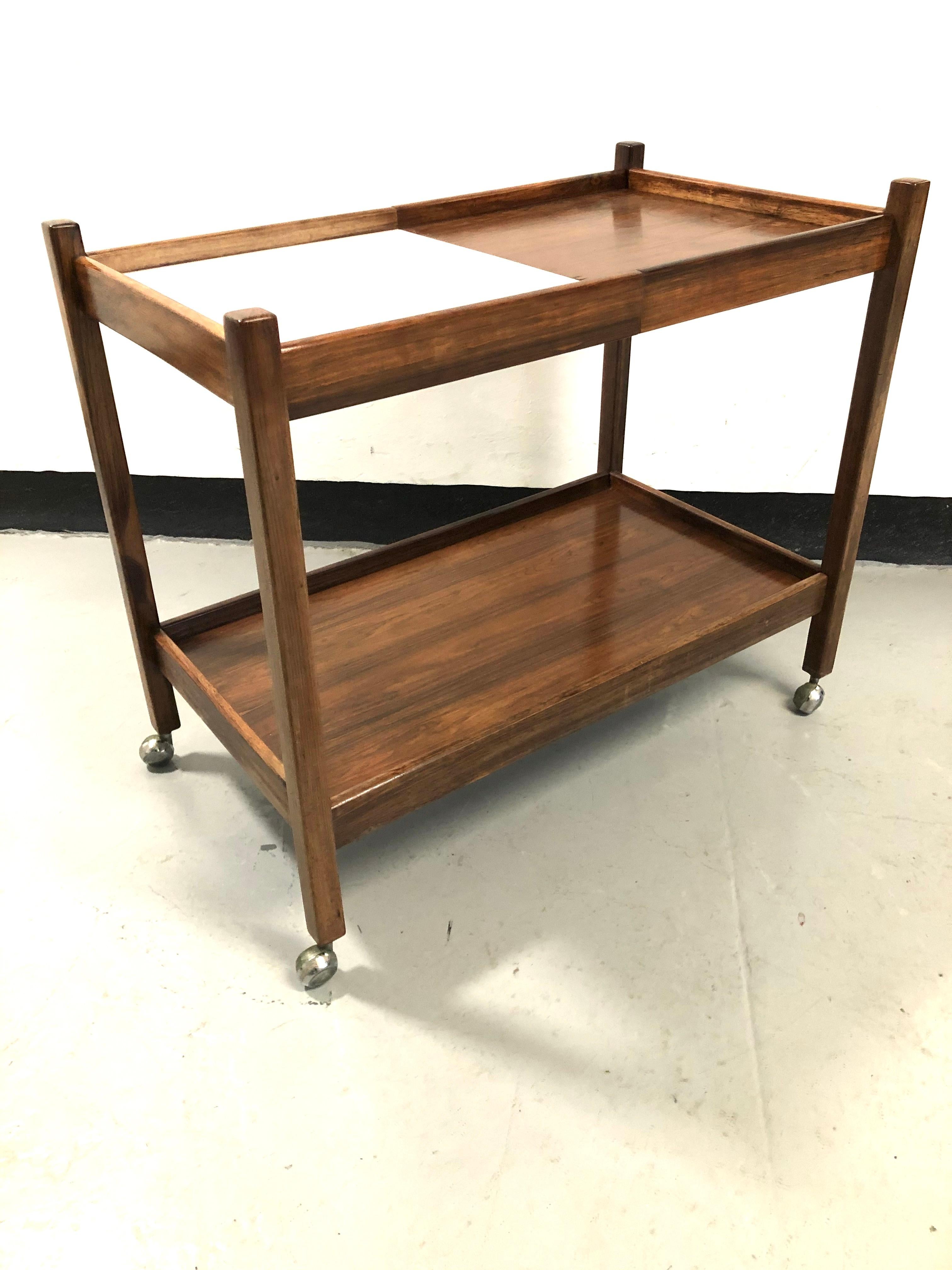 1960s Brazilian drinks trolley designed by Sergio Rodrigues.

With removable and reversible trays. The top is divided in half and has white laminate on one side and wood finish on the reverse side, allowing for a combination of looks.

The bottom