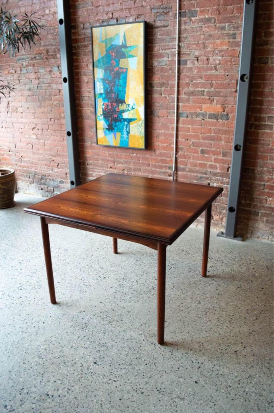 Fresh from restoration, we are pleased to offer an exquisite dining table crafted from beautifully figured Brazilian rosewood. Made in Denmark in the 1960s, this piece features a draw leaf mechanism whereby the leaves are self-stored underneath the