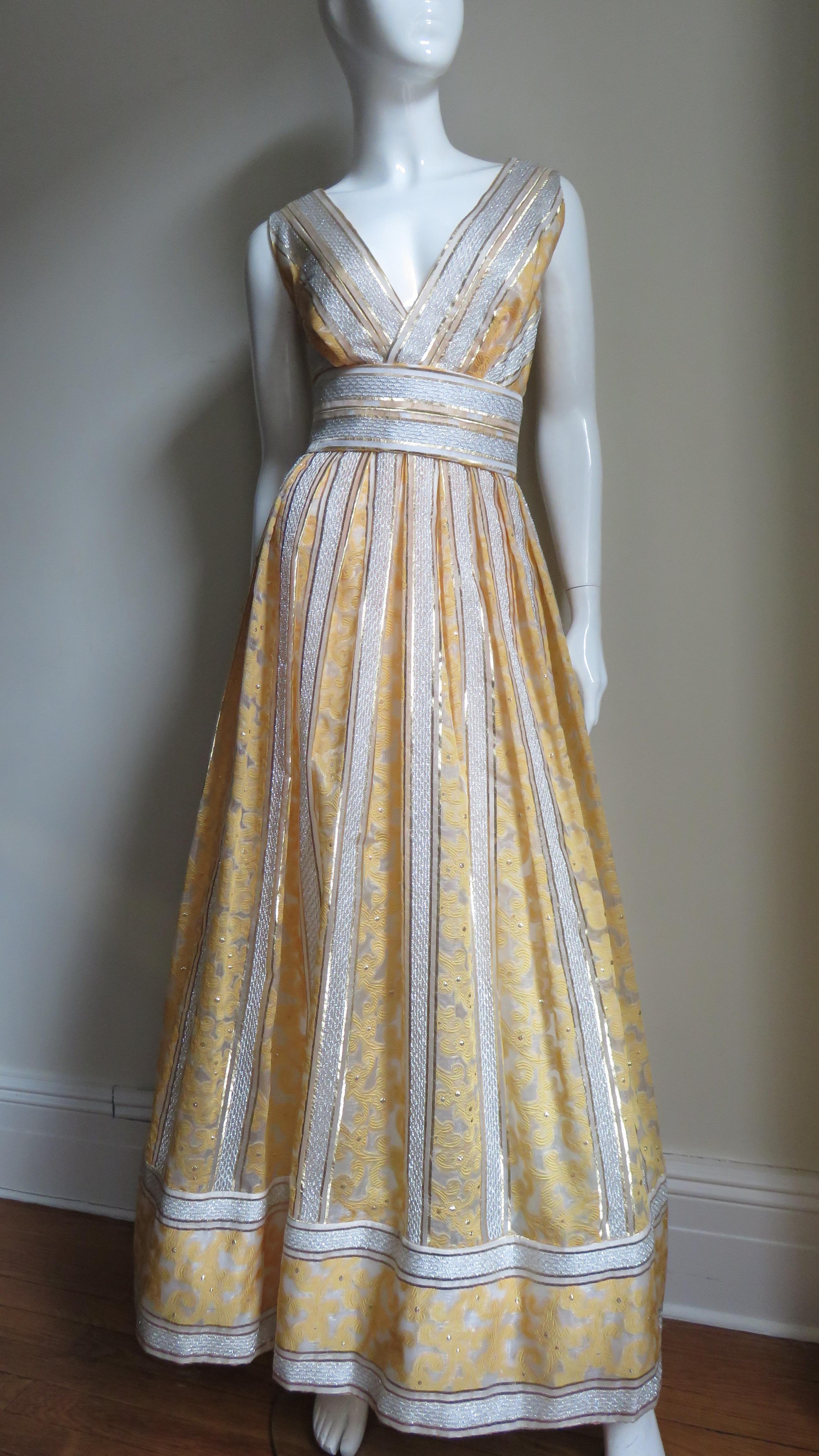 A beautiful silk gown from Kent Originals made in British Hong Kong known for beautiful detailed works.  The fabric consists of a golden scroll pattern and silver thread shot geometric pattern both against a sheer off white background with