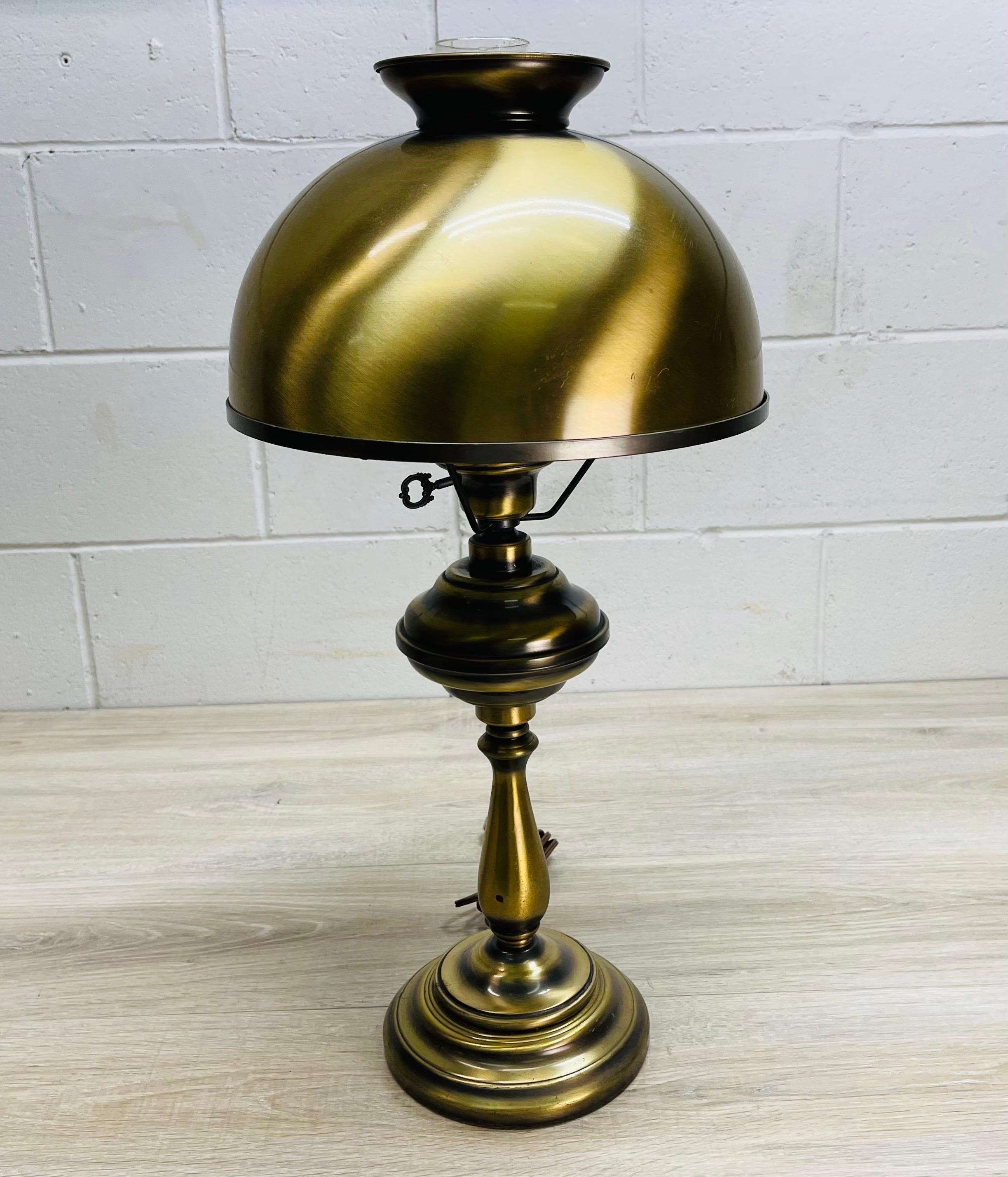 Vintage 1960s brushed brass round table lamp. The lamp comes with the metal shade and glass chimney. Wired for the US and in working condition. Uses a standard 100W bulb. Shade does have two small dents in the metal but can be used in the back of