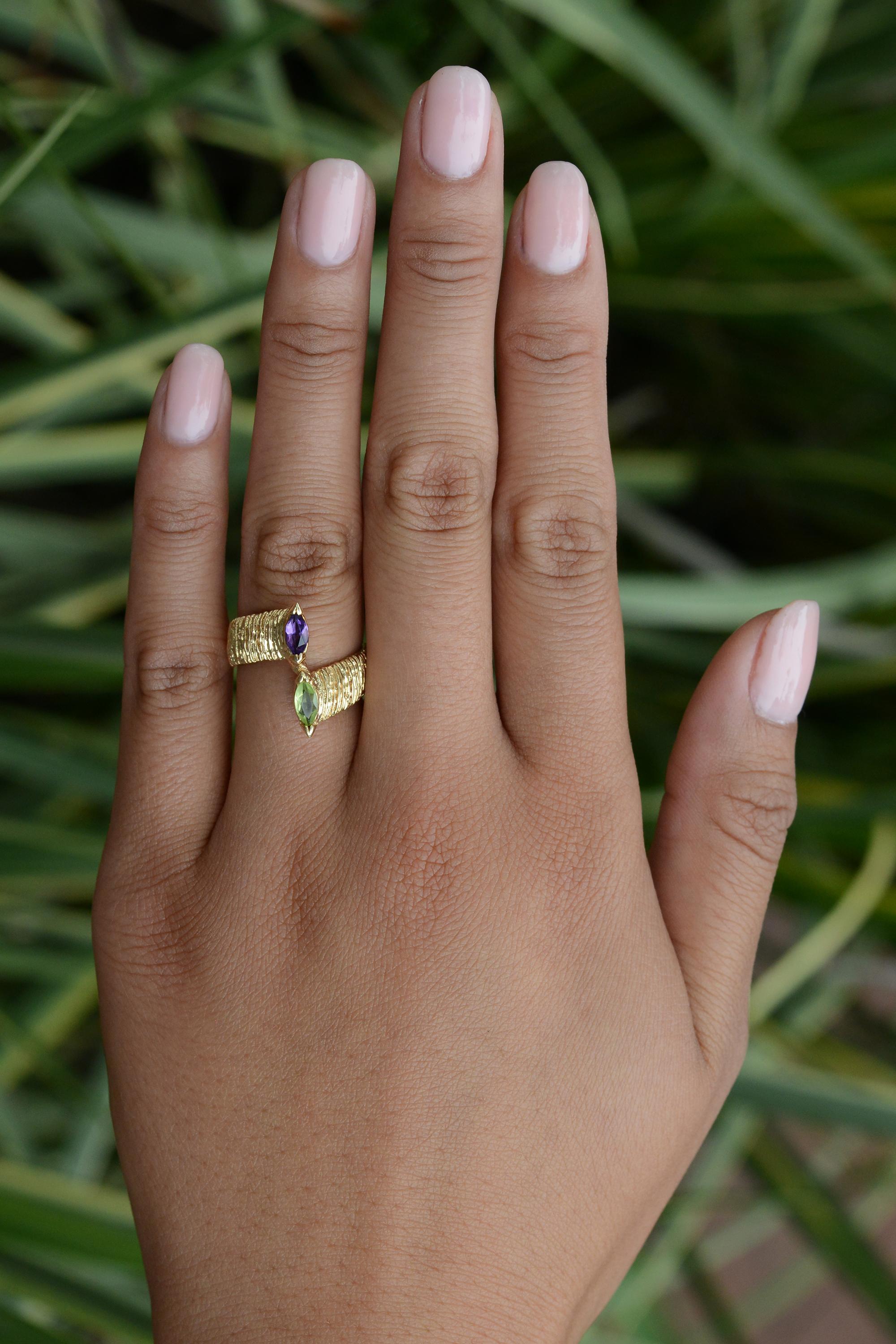 Sure to strike a conversation, this beautiful Brutalist vintage 1960s gemstone cocktail ring features two natural gemstones - an amethyst and a peridot - in a classic French toi et moi bypass setting. Crafted in a rough textured 14 karat yellow