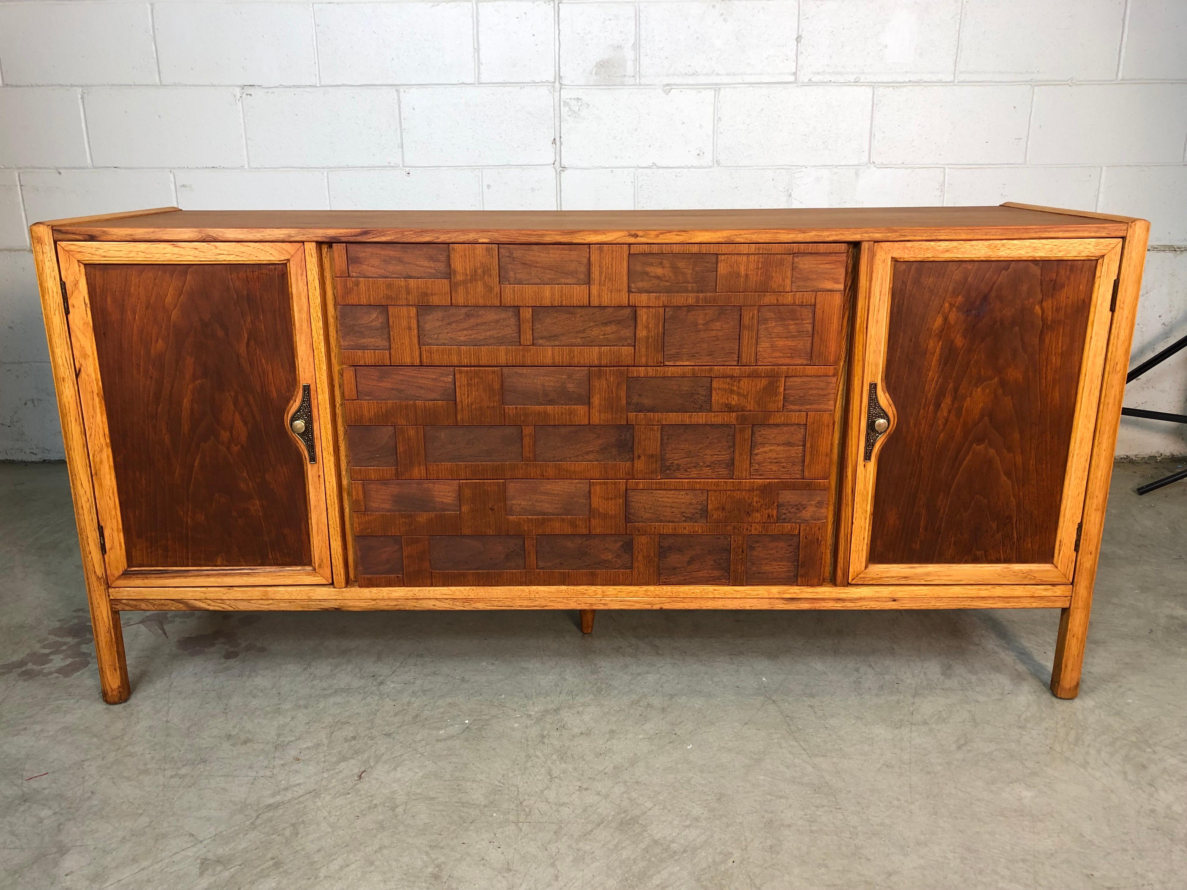 Mid-Century Modern 1960s Brutalist style walnut and ashwood dining room credenza. The credenza has three drawers for storage and two side doors for additional storage. The credenza also has a 5th leg for additional support. The credenza has been