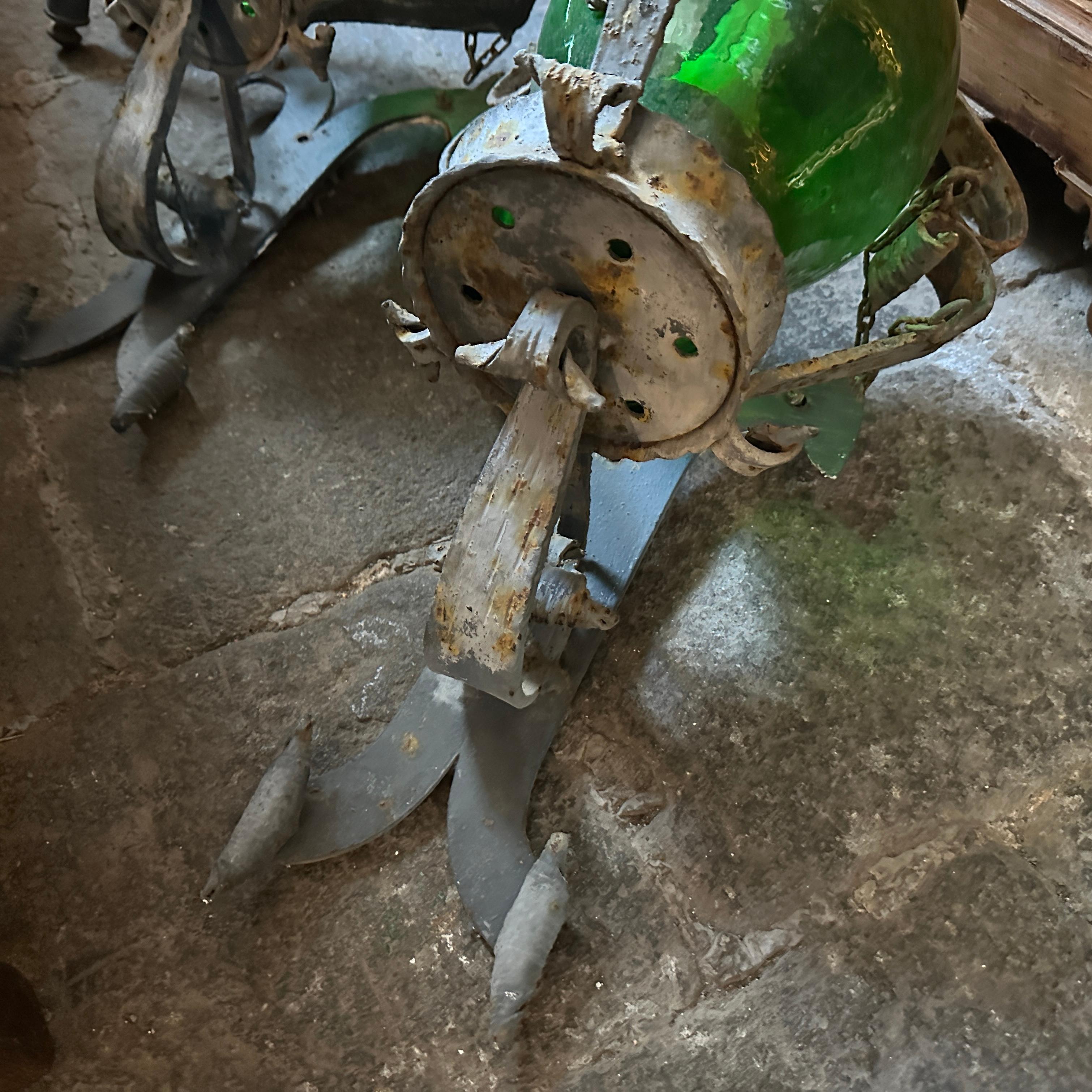 Thiese 1960s Brutalist Italian huge wall sconces have  been made of wrought iron and green glass. The design is robust and striking, featuring a heavy, hand-forged iron frame that exudes a sense of ruggedness and strength typical of the Brutalist