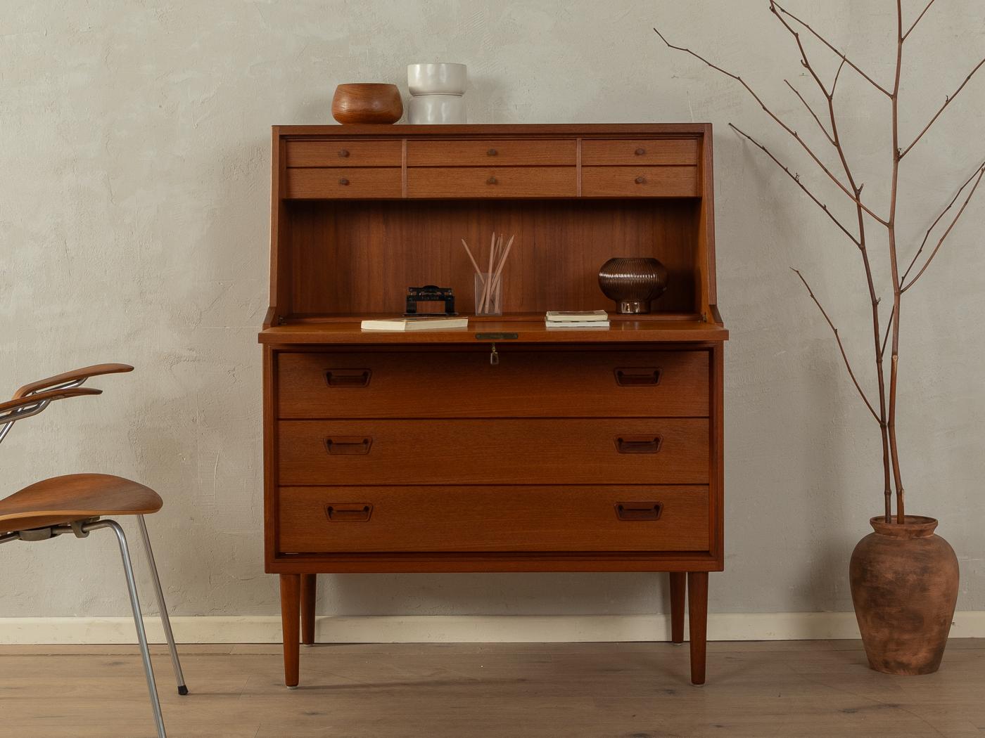 Classic secretary from the 1960s by Munch Møbler. High-quality corpus in teak veneer with a hinged work surface, six interior drawers, three drawers and cigar shaped feet.
Quality Features:

    accomplished design: perfect proportions and visible