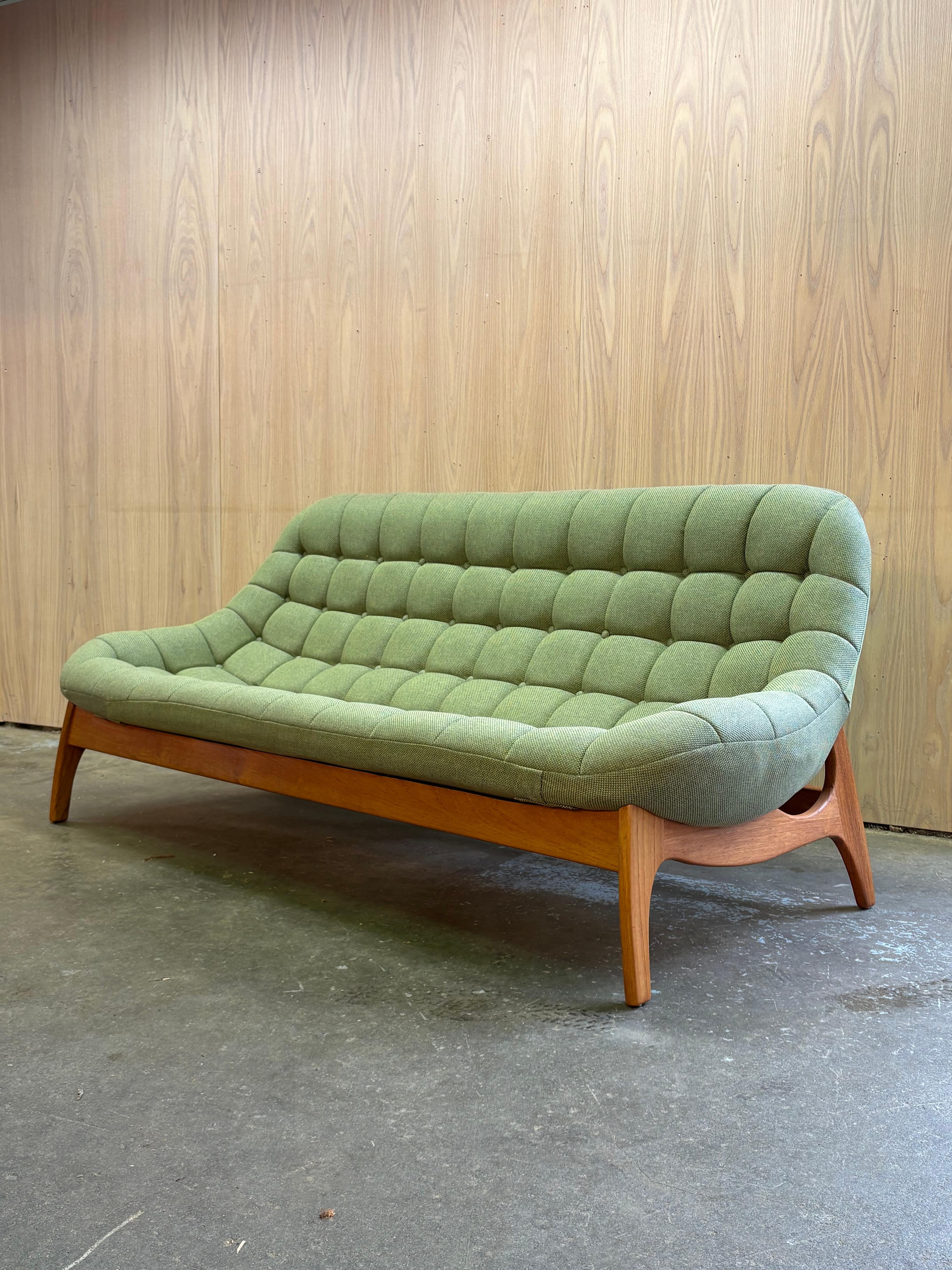A sculptural Canadian classic from the 1960s, this R. Huber “Scoop” sofa captures the smooth, organic elegance of the era. The beautifully curved fiberglass shell rests on a solid teak base with graceful, sculpted lines that flow seamlessly from