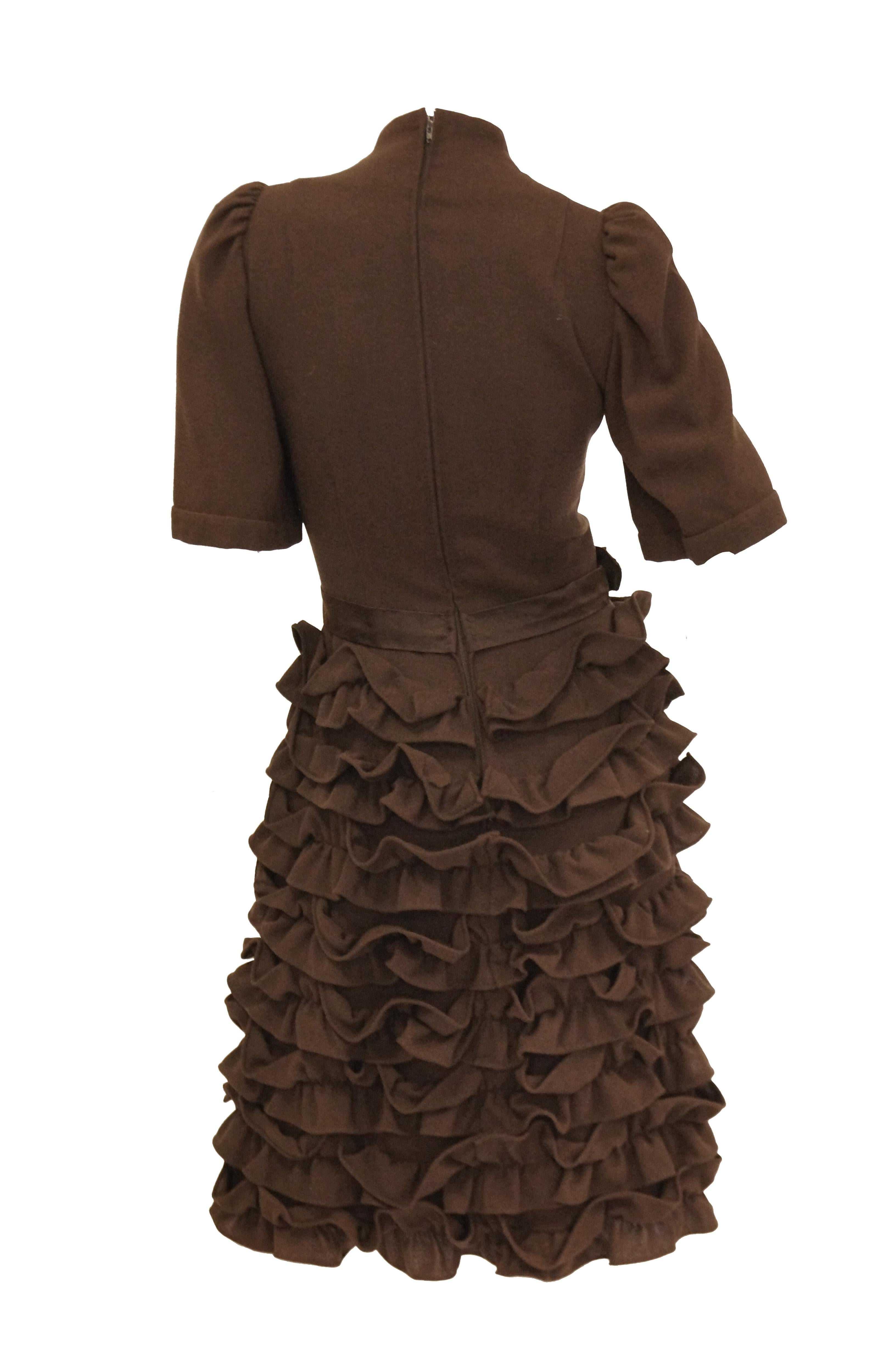 Delightful chocolate brown cocktail dress! The dress is knee length, with slightly puffed shoulders, sleeves that fall just above the elbow, and a faux turtleneck. The dress has, for the most part, a fitted sheath silhouette. The playful skirt is