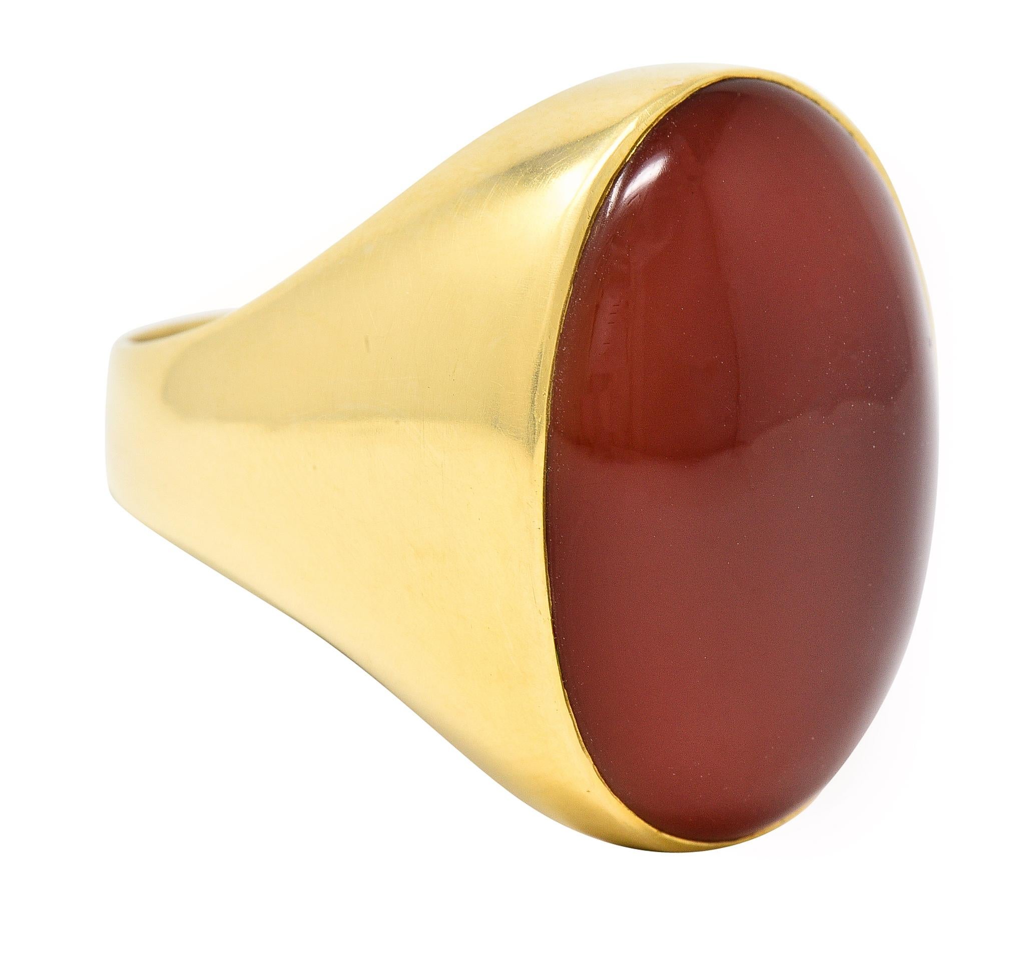 Le cabochon de cornaline de forme ovale mesure 17,5 x 25,0 mm. Couleur orange rougeâtre moyen translucide. Encastré dans un cadre en or. Estampillé pour l'or 18 carats. Circa : 1960's. Taille de la bague : 10 1/2 et assez grande. Elle mesure 25,5 mm