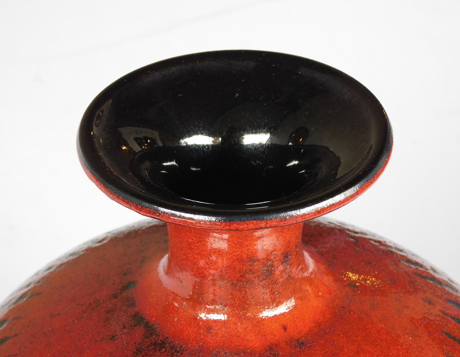 With flaring neck above a portly body all in a fiery red-over-black glaze; raised mark to underside.
