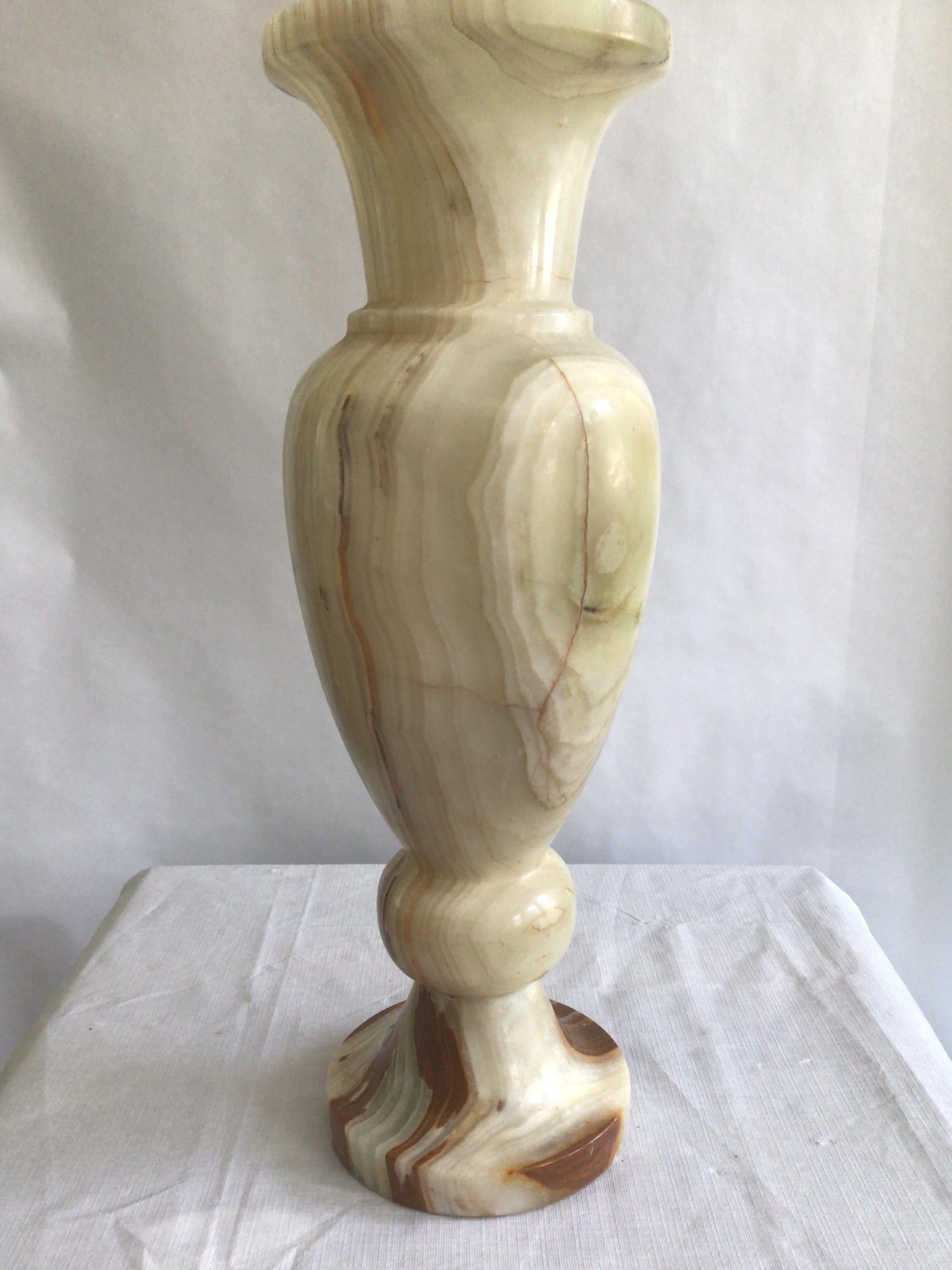1960s Carved Onyx Urn Vase
This elegant large vase is composed of layers of cream and earthy green onyx banding. With contrasting circular splashes of red and brown running down one of its sides, it has been hand-carved and polished