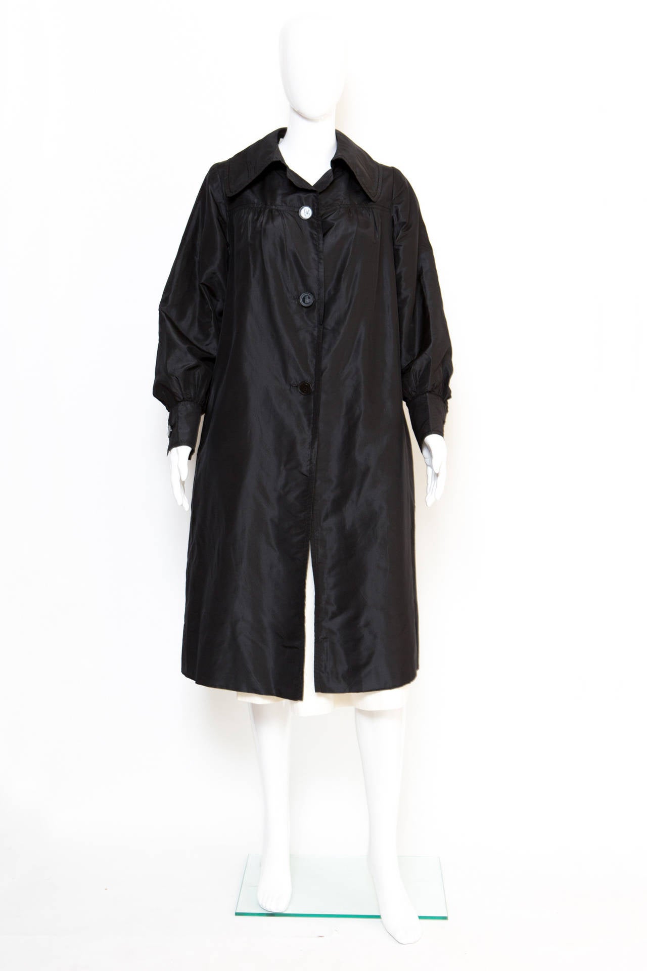 trench-coat en soie noire des années 1960 de Carven, avec un col classique, des manches longues, des poignets à boutons logo, des poches latérales et une fermeture à boutons sur le devant avec des boutons logo. Ce trench est entièrement doublé.
En