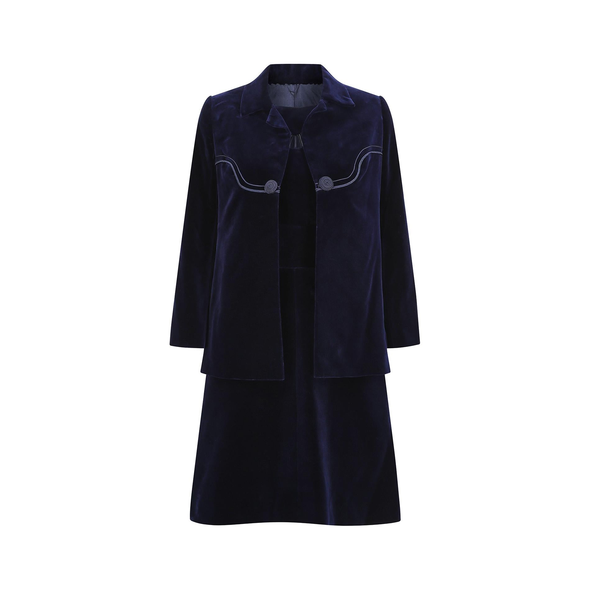 Ce tailleur haute couture bleu nuit des années 1960 est magnifiquement confectionné dans un velours luxueusement doux. La robe présente une simple encolure dégagée avec une découpe sur le devant, avec un détail de corde presque semblable à un rayon.
