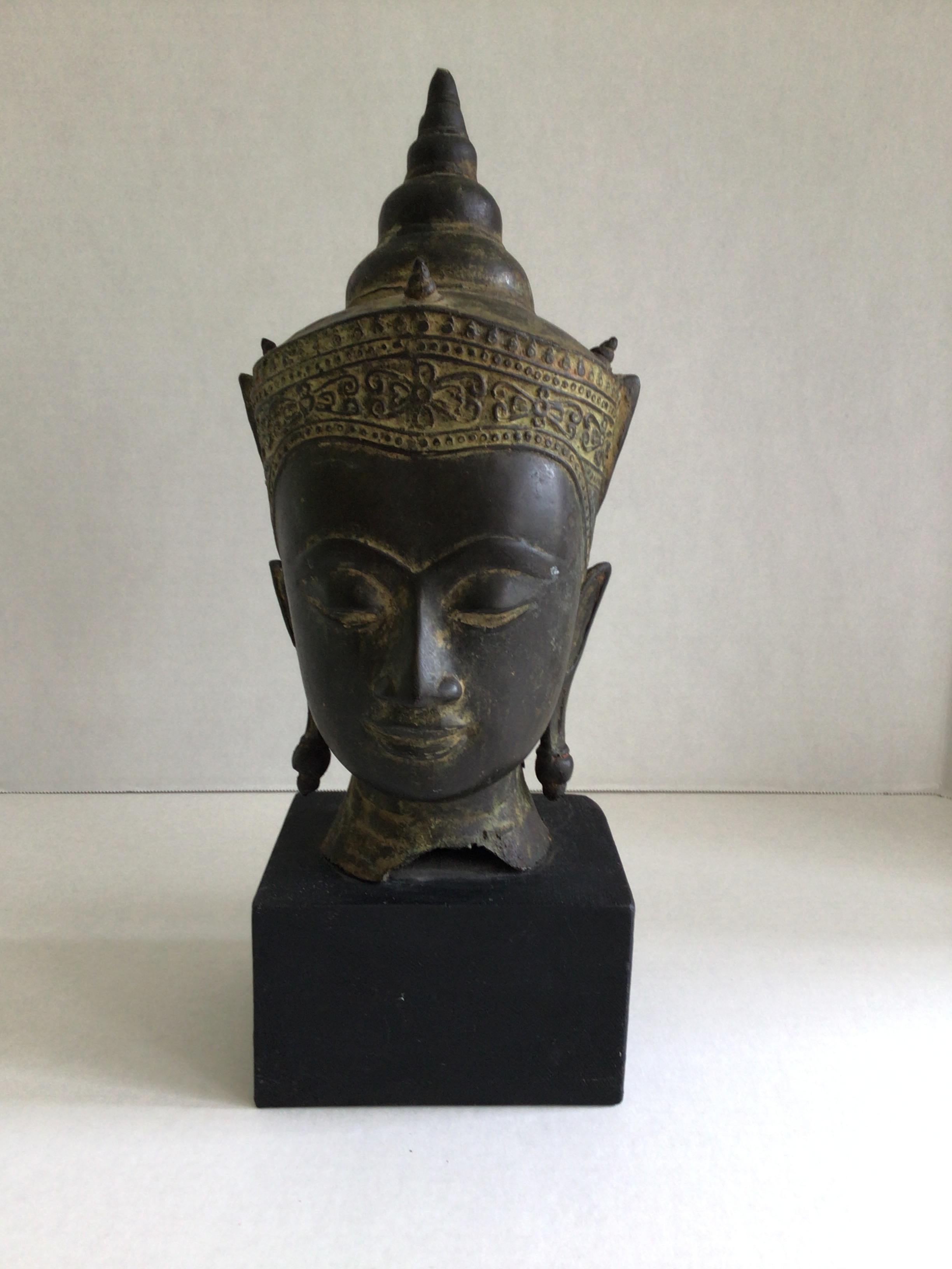 Testa di Buddha tibetano con corona in bronzo fuso del 1960 su base in Wood Wood dipinto
Il viso ha un'espressione meditativa
Occhi semichiusi e sopracciglia arcuate, naso allungato e labbra chiuse.
La testa è coronata da un Diadema ornato e da un