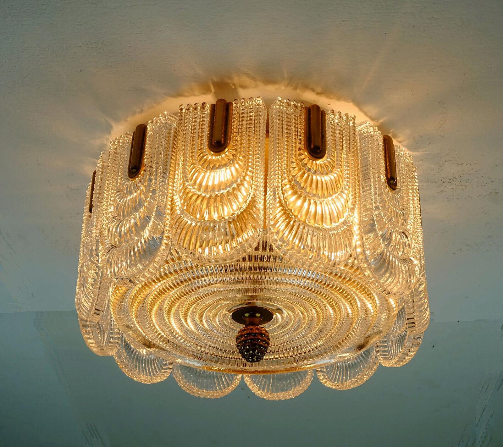 Fantastic and glamorous vintage 1960sceiling lamp. The base is made of brass. The ceiling base and fasteners are made of brass, the shade consists of 12 rectangular elements and a round disc made of structured glass. Holds 6 E14 bulbs.

Pre-used,
