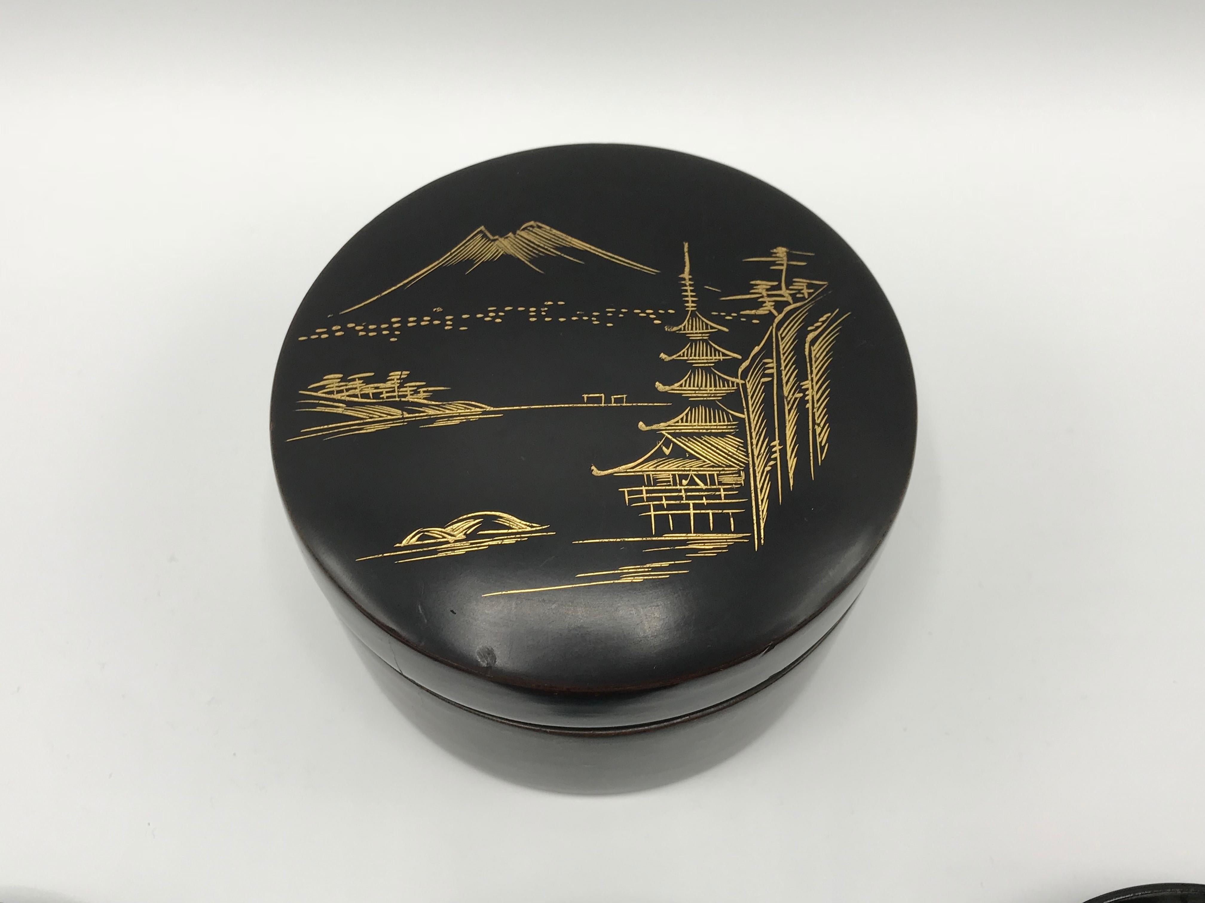 Listed is a fabulous, set of 6, 1960s black and gold lacquered coasters. The set includes a matching lidded box, where all six of the coasters stack inside. 

Measures: Box 2.25in height x 3.75in diameter
Coasters 0.25in height x 3.25in diameter.