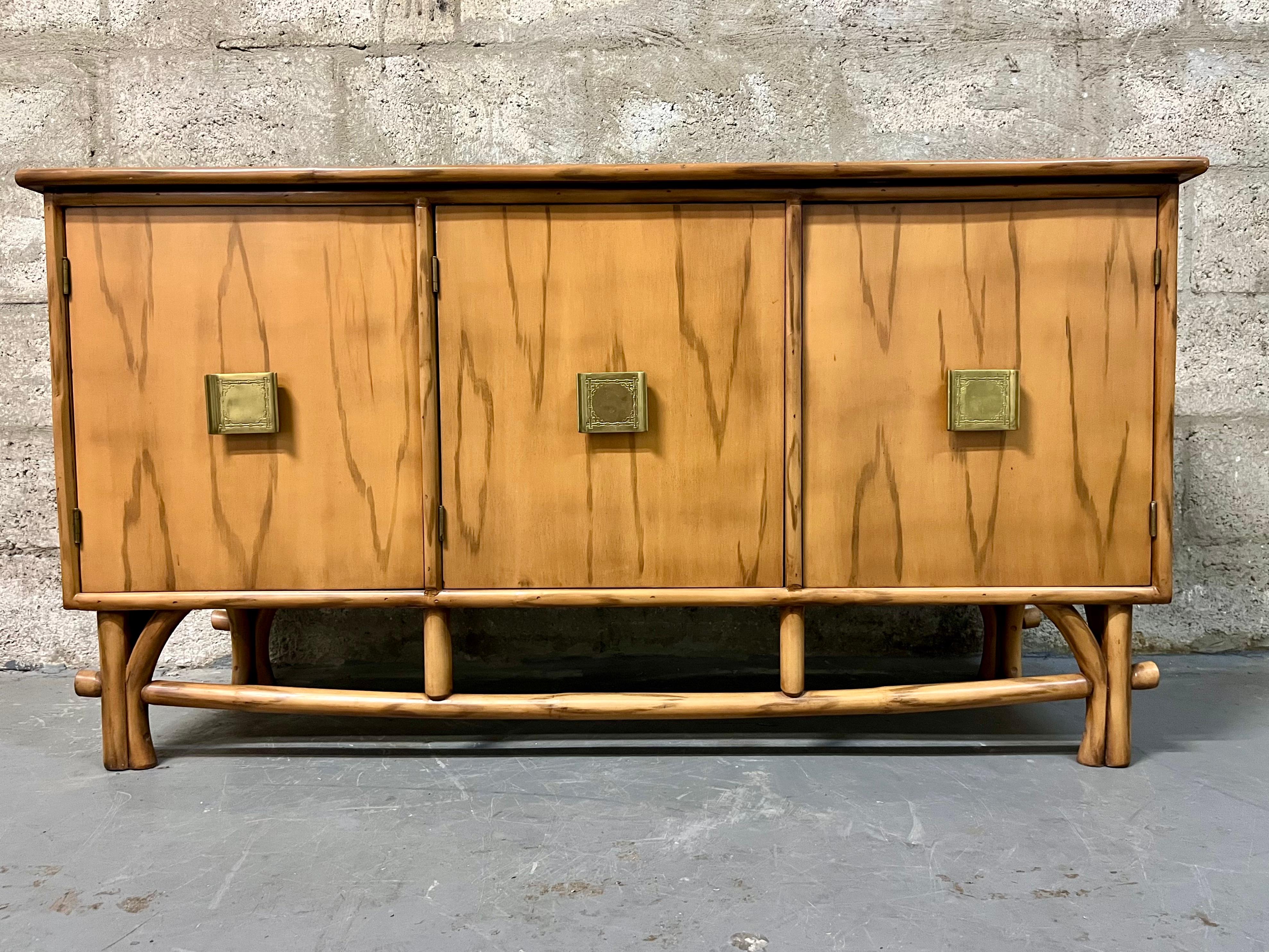 Mid Century Modern Chinoiserie Inspired Rattan Buffet / Sideboard in the Adrien Audoux & Frida Minet Style. C 1960s.
Features a compact size that will work in any small area or room, a faux wood grain finish with rattan legs, a faux marble stucco