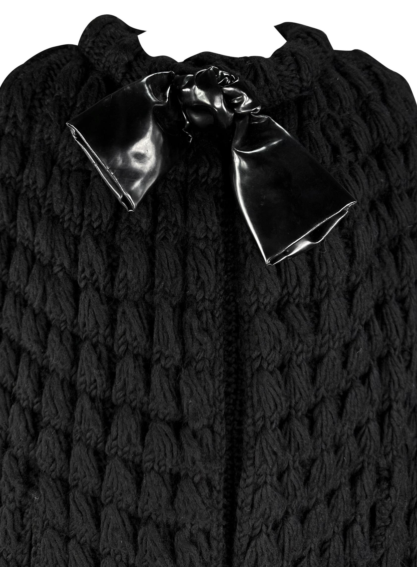 Marc Bohan designed this chic black Christian Dior knit cocoon coat in the 1960s. This vintage coat is entirely woven, featuring a fringe hem and black leather bow at the neckline. With slits to stick your arms out of, this Christian Dior cocoon