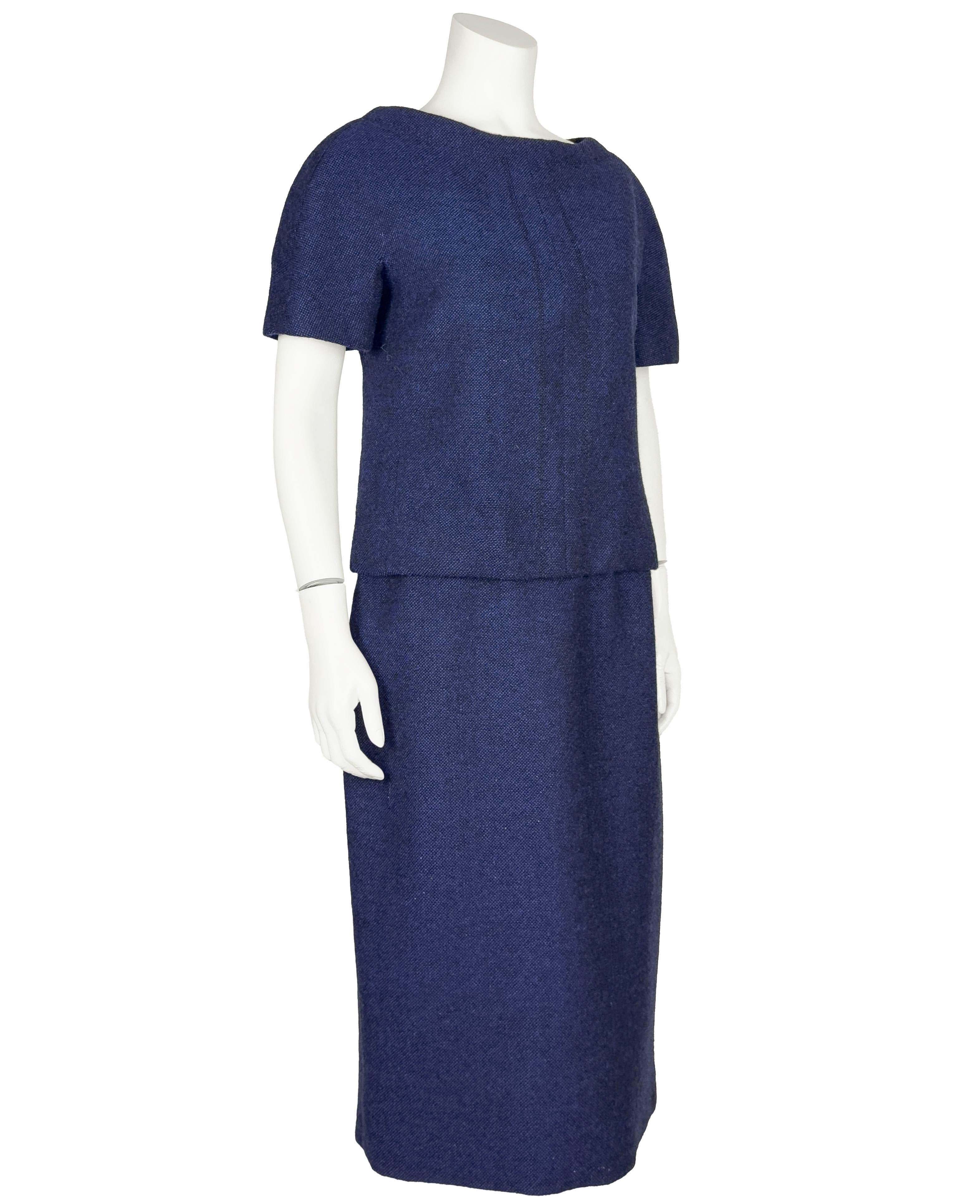 Christian Dior London del 1960, abito in tweed di lana blu scuro a maniche corte e due strati, realizzato in modo da sembrare un top e una gonna separati, ma in realtà è un abito unico con doppia cerniera. La lana intrecciata blu e nera conferisce
