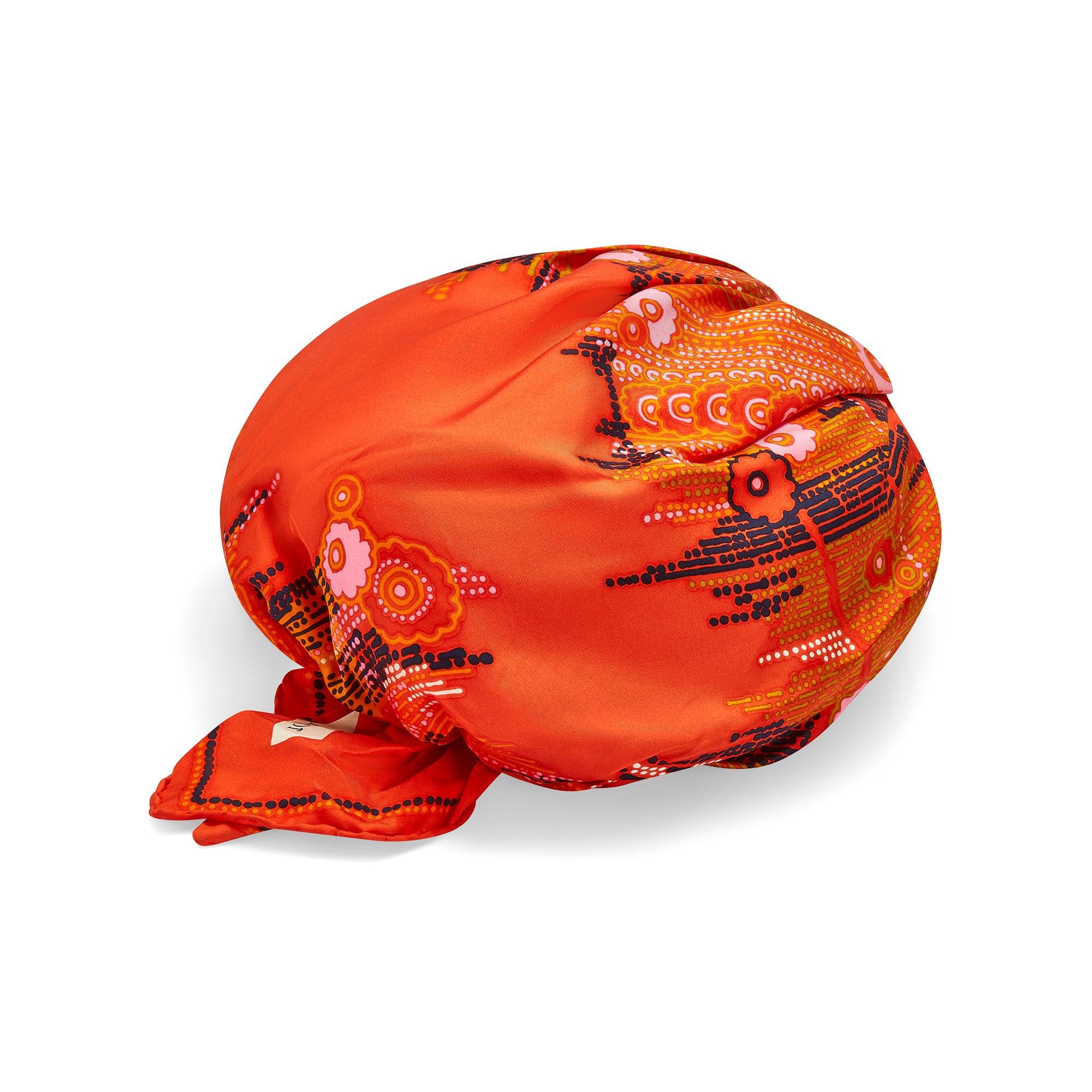 This elegant turban was designed by Christian Dior in the late 1960s. The epitome of chic, these hats were featured in the April 1968 edition of Vogue. Designed to look like a tangerine orange silk head scarf wrapped around the head, it is printed