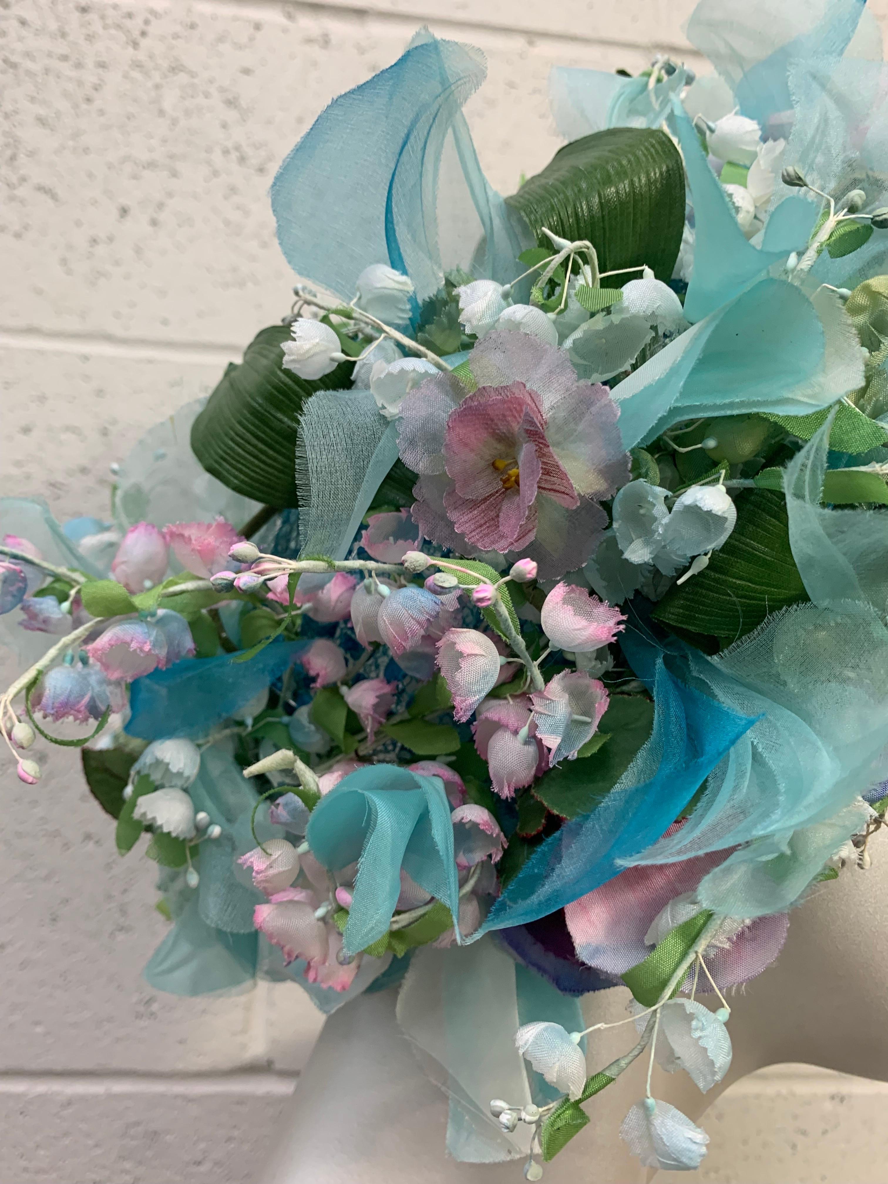 A truly spectacular 1960s Christian Dior Pastel Floral Hat:  A wreath or turban with open netted crown in pastel silks of turquoise, green, purples and white lily of the valley. Blue open net crown. Lots of volume and drama in this beauty!  Its not