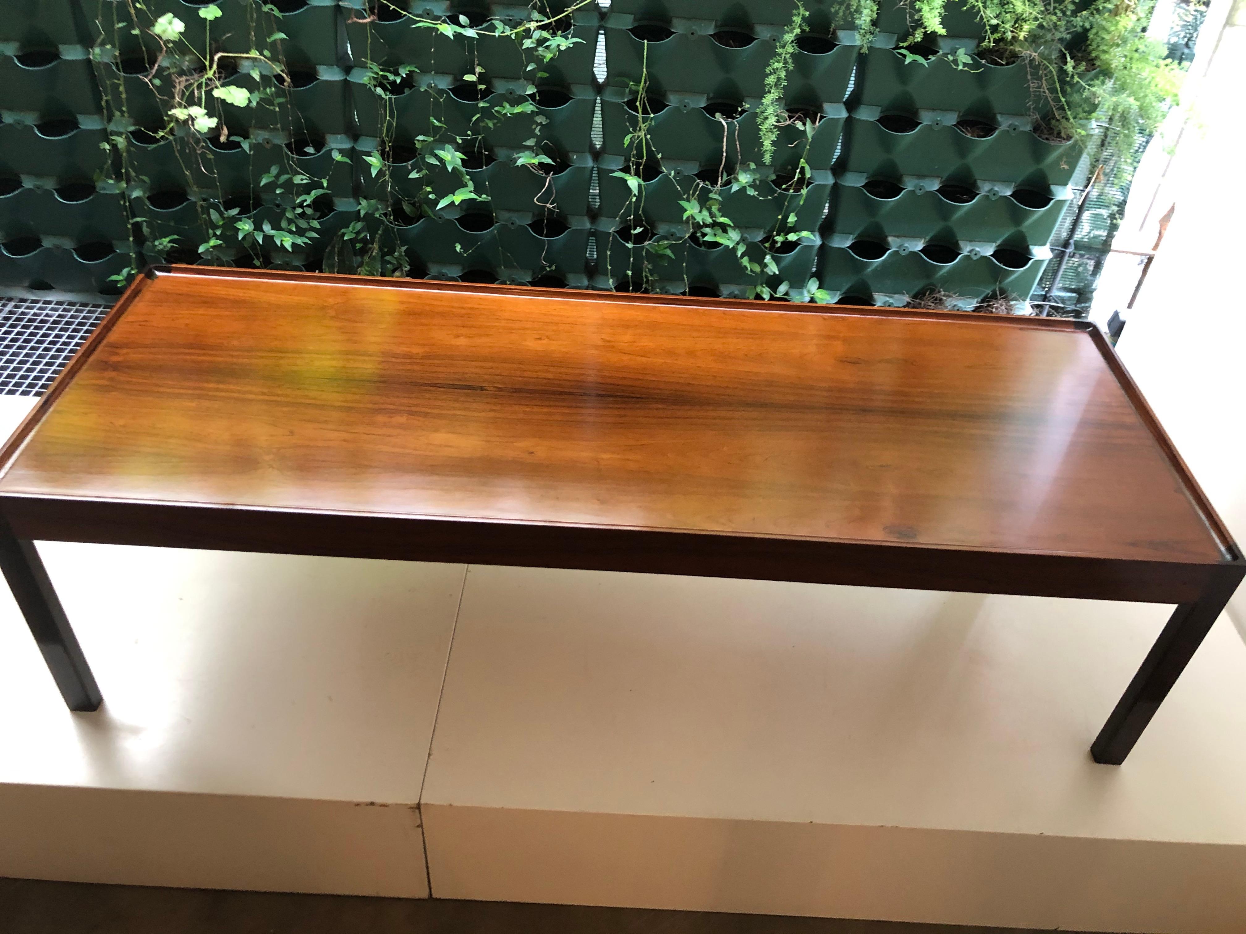 A generously proportioned Danish coffee table in highly figured Brazilian rosewood. The long tabletop has angled edges and is thick enough for the piece to double as a bench.