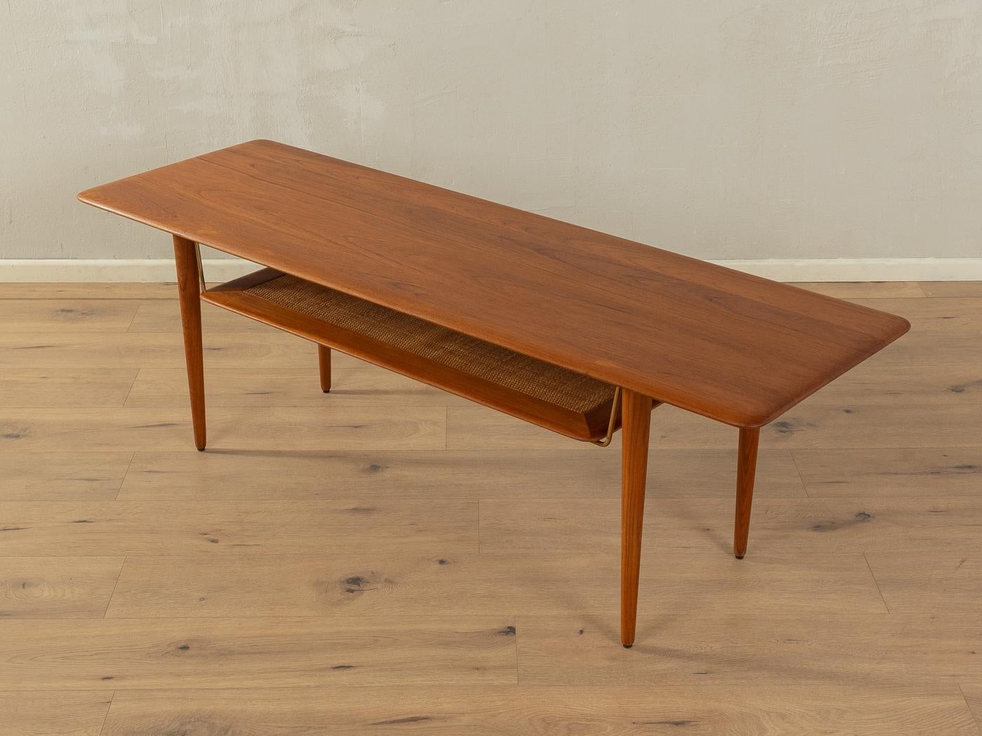 Classic coffee table from the 1960s by Peter Hvidt & Orla Mølgaard-Nielsen for France & Daverkosen. Rare model FD- 516. Frame and table top made of solid teak with an additional shelf made of rattan wicker supported by brass fittings.

Quality