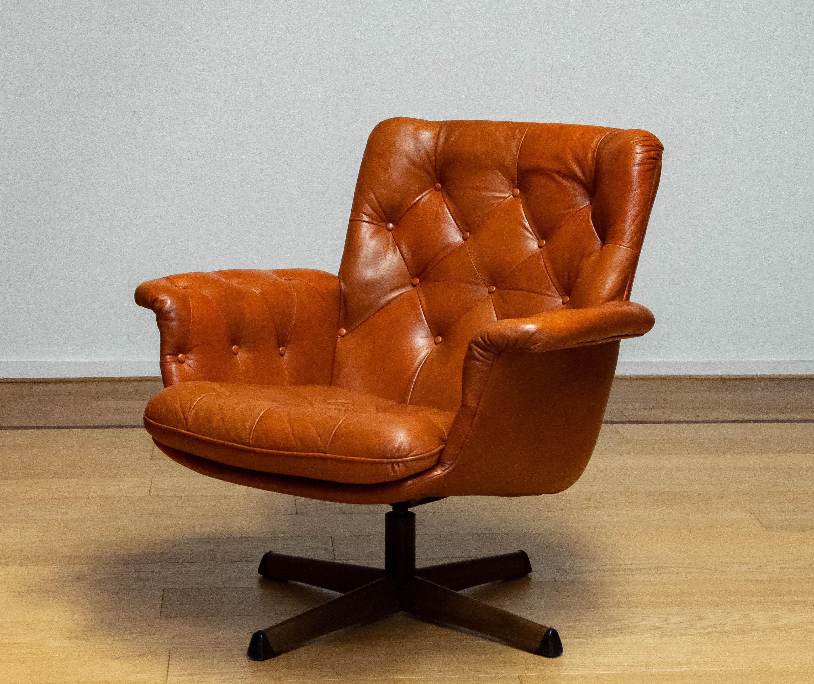 Ein schöner Drehstuhl von Göte Möbler Nässjö Schweden, 1960er Jahre.
Dieser Stuhl ist mit getuftetem cognacfarbenem Leder gepolstert und steht auf einem drehbaren Metallgestell mit Holzdruck.
Der Stuhl ist sehr bequem und sieht sowohl in klassischen