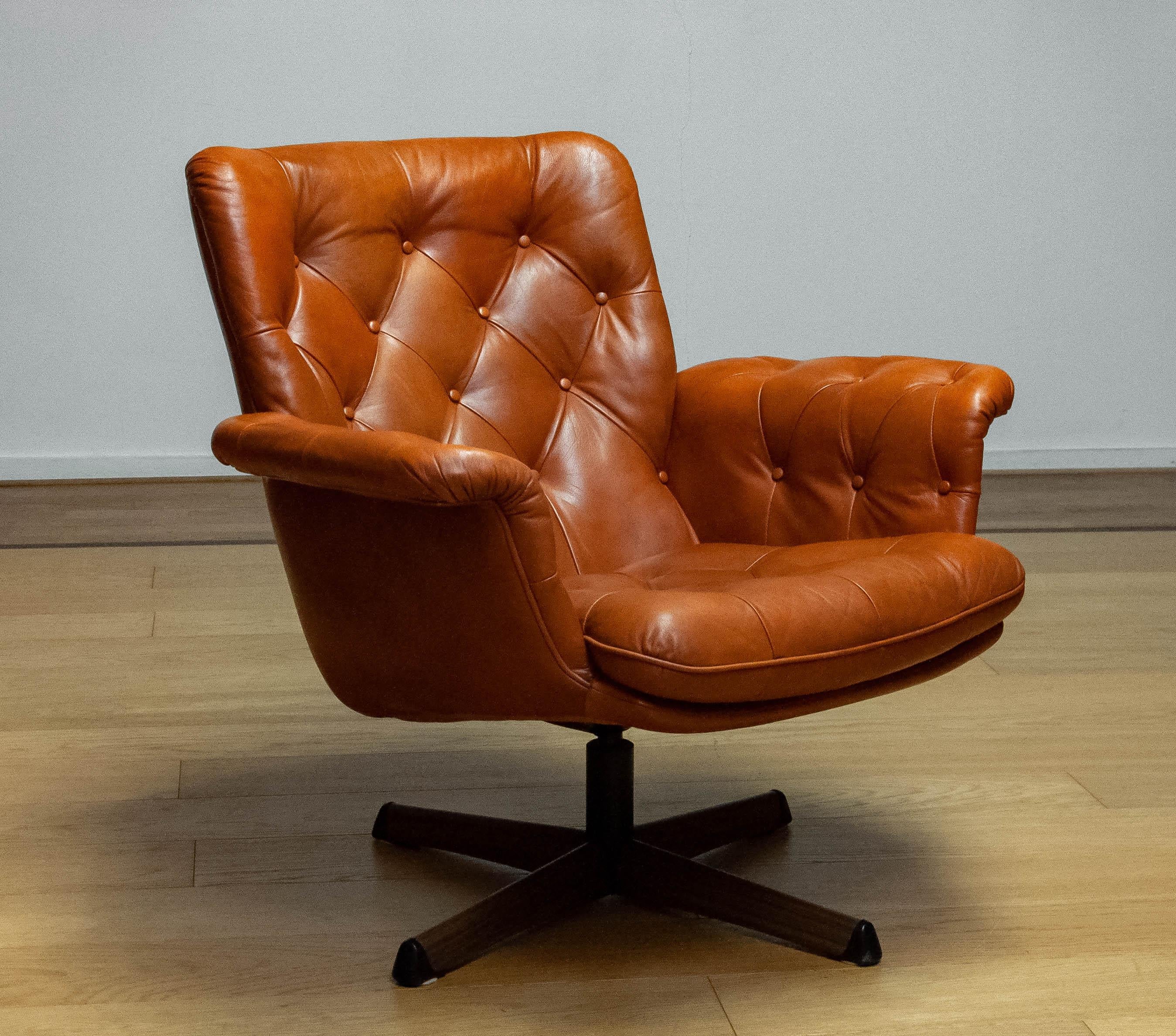 Magnifique fauteuil pivotant fabriqué par Göte Möbler Nässjö Suède, années 1960.
Cette chaise est recouverte de cuir cognac tufté et repose sur un pied pivotant en métal avec une empreinte de bois.
La chaise est très confortable et s'intègre