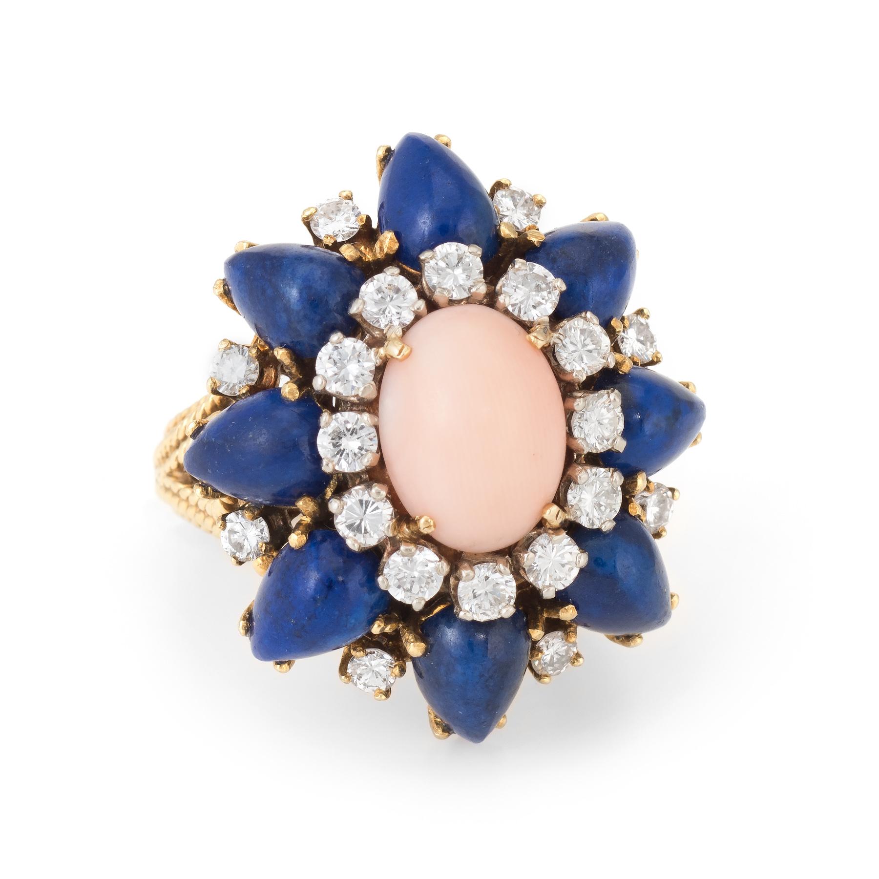 Finely detailed vintage cocktail ring (circa 1960s), crafted in 14 karat yellow gold. 

Centrally mounted angel skin coral measures 10mm x 7.75mm (estimated at 2 carats) is accented with 8 pieces of cabochon cut pear shaped lapis lazuli that
