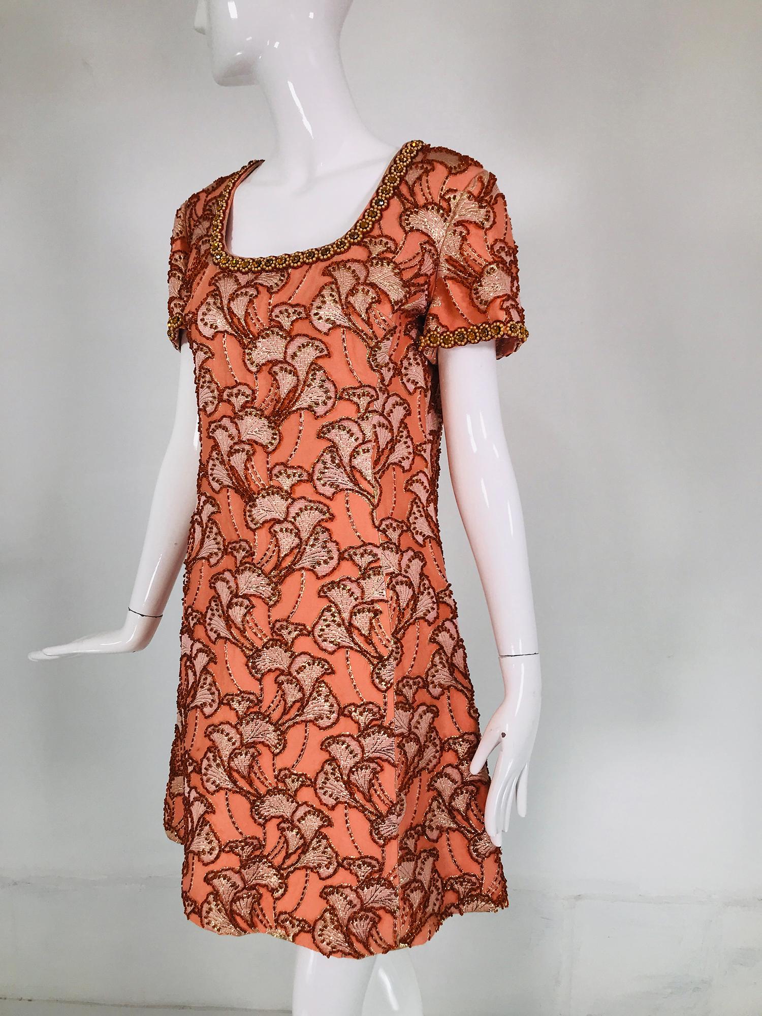 1960s coral silk brocade, hand beaded 1960s mini dress by Royal Cathay, Hong Kong. Scoop neck, short sleeve princess seam dress with a jewel neckline and sleeve cuffs with pearls and prong set orange faceted rhinestones. The dress has gold metallic