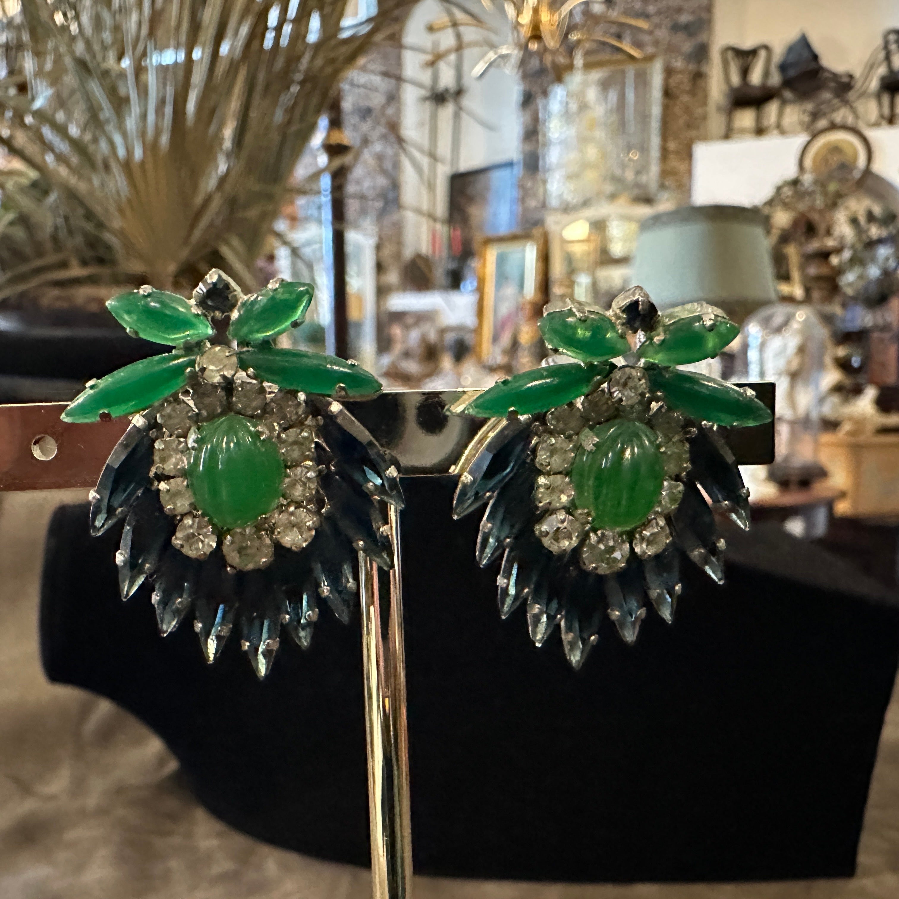 These 1960s Christian Dior costume jewelry clip-on earrings showcase a luxurious and nature-inspired design. Crafted in a silver-tone metal setting, each earring features an intricate arrangement of marquise-cut and round rhinestones, with a color