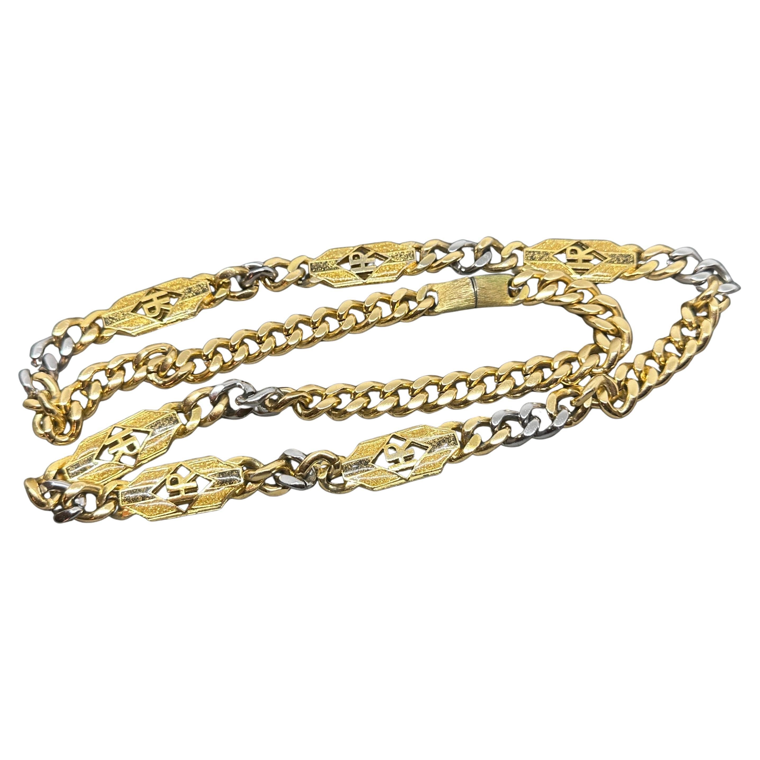 Questo gioiello di bigiotteria, disegnato da Helena Rubinstein, presenta una collana a catena dal sorprendente design bicolore. La catena è caratterizzata da maglie larghe e intrecciate che alternano le finiture oro e argento, creando un contrasto