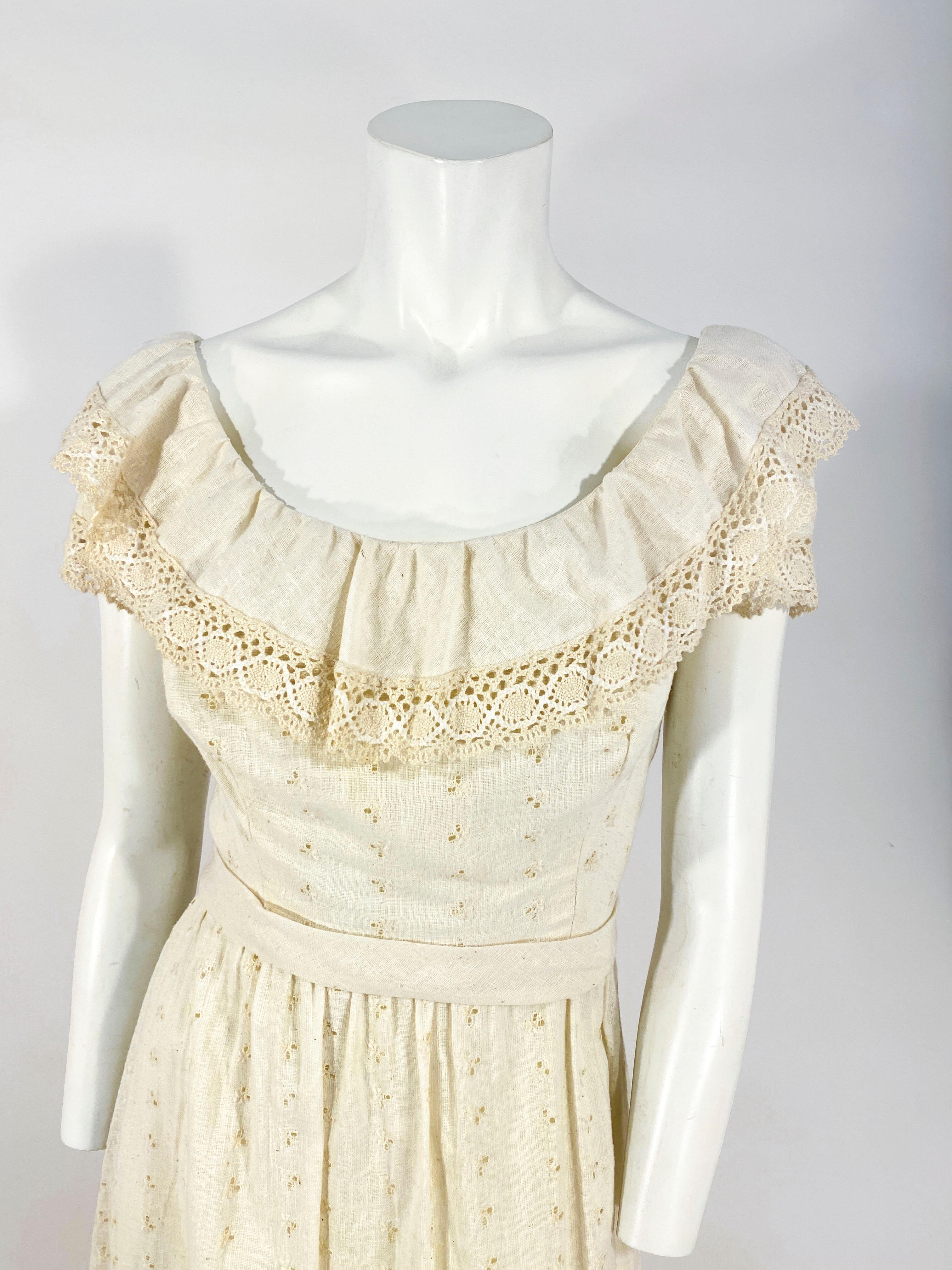1960s custom made dress with eyelet accents, machine crochet inserts in 4 bands on the skirt, ruffled off-the shoulder neckline, cap lace sleeves, and an applied waistband. The back has a zipper closure.
